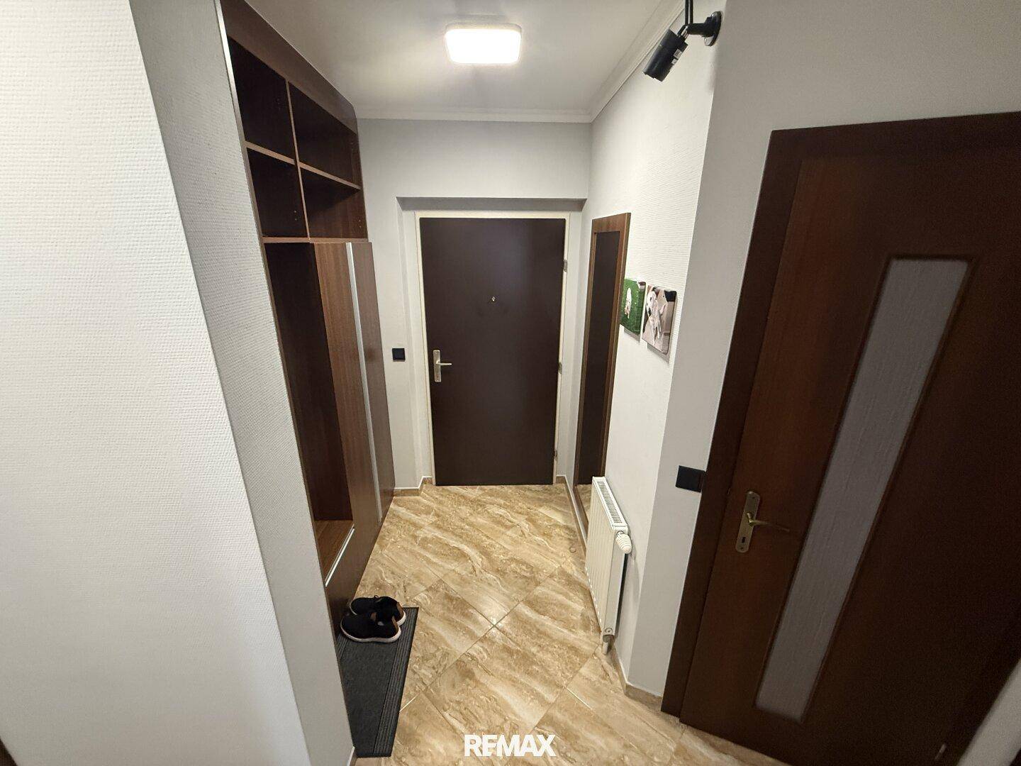 Heller Flur mit gemusterten Fliesen, Einbauschrank und dunklen Holztüren.
