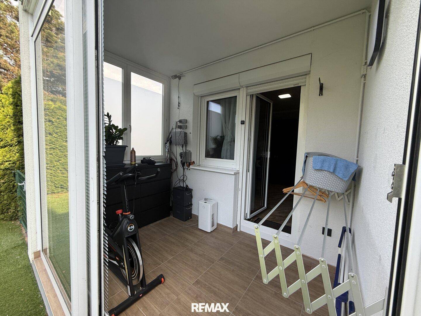 Verglaster Balkon oder Wintergarten mit Trainingsrad und Wäscheständer.