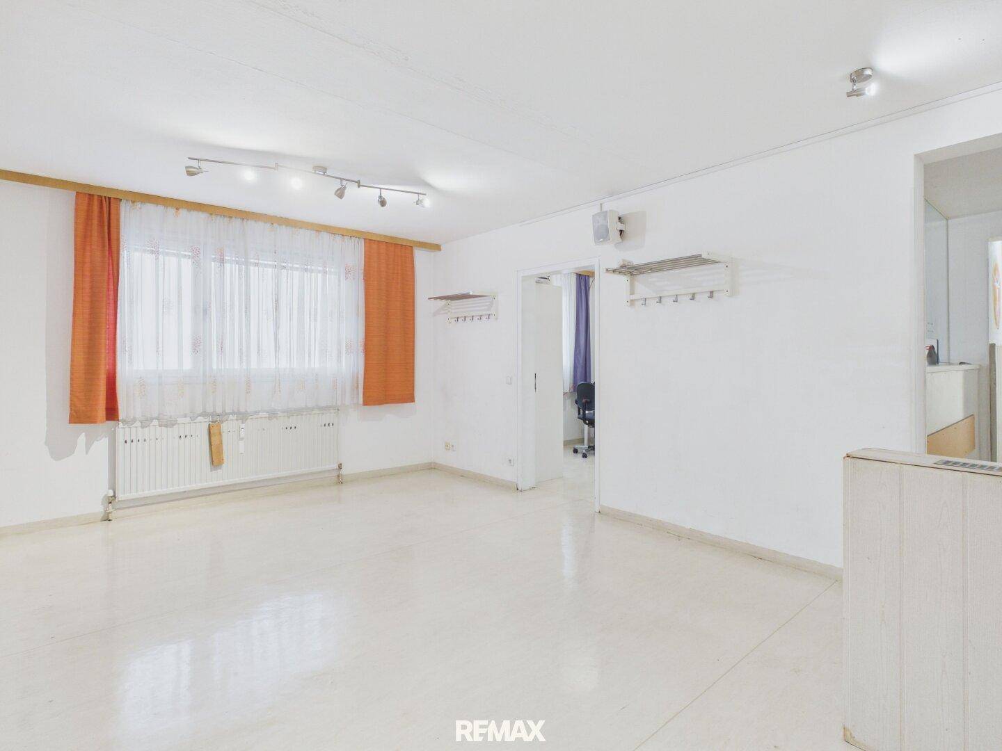 Geräumiges, helles Zimmer mit großen Fenstern und Zugang zu einem weiteren Raum.
