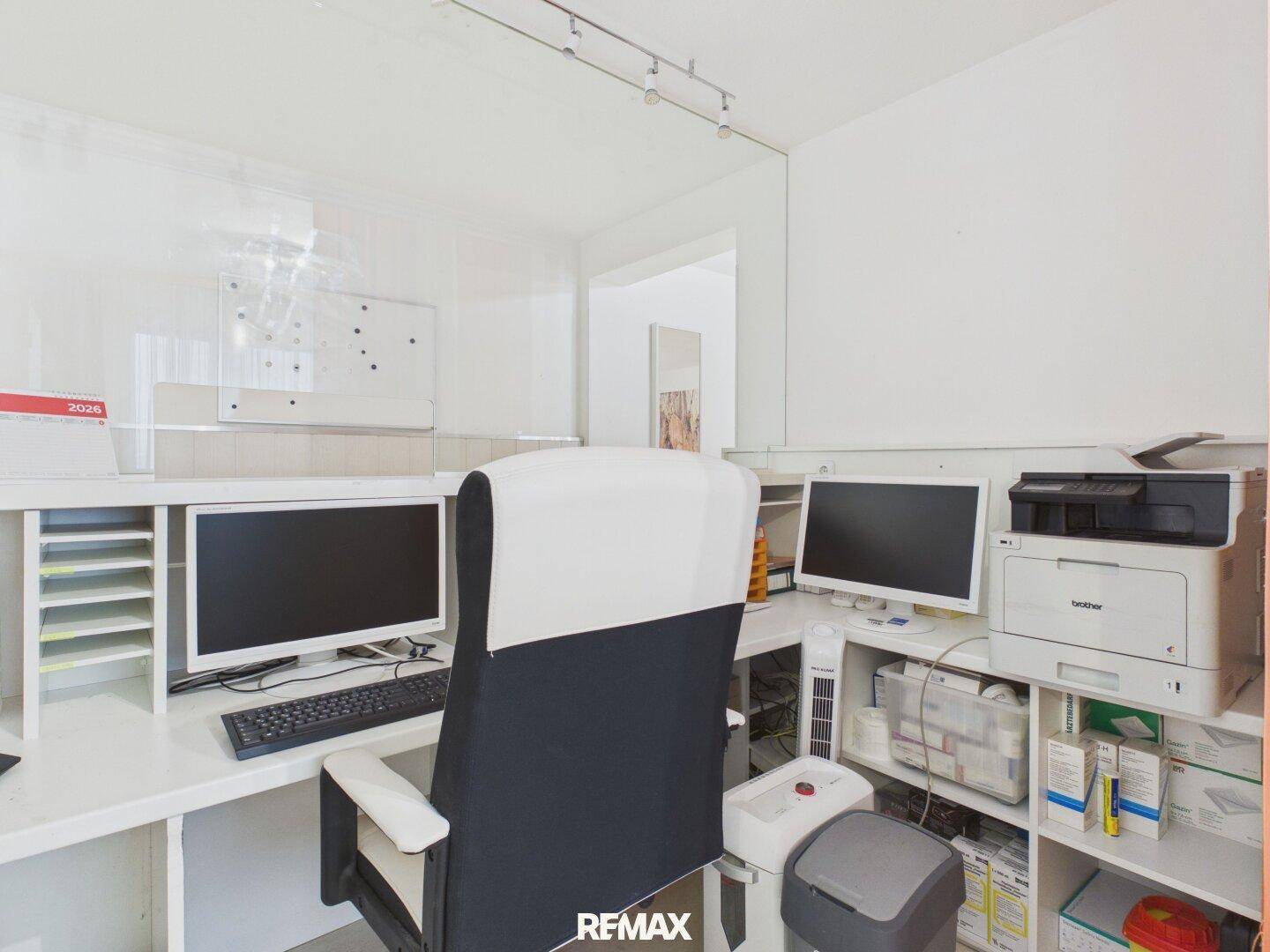 Funktionaler Bürobereich mit zwei Computern, Drucker und Ablagesystemen, bereit für den Arbeitsalltag.
