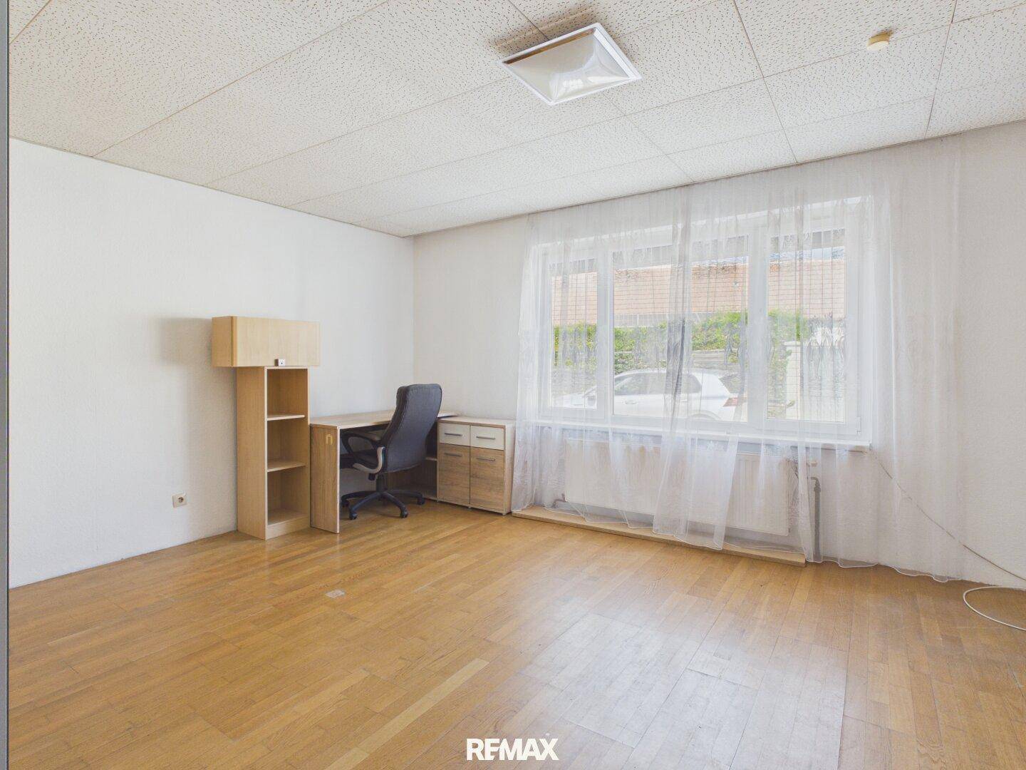 Arbeitszimmer mit Schreibtisch, Regal und großem Fenster für viel Tageslicht.