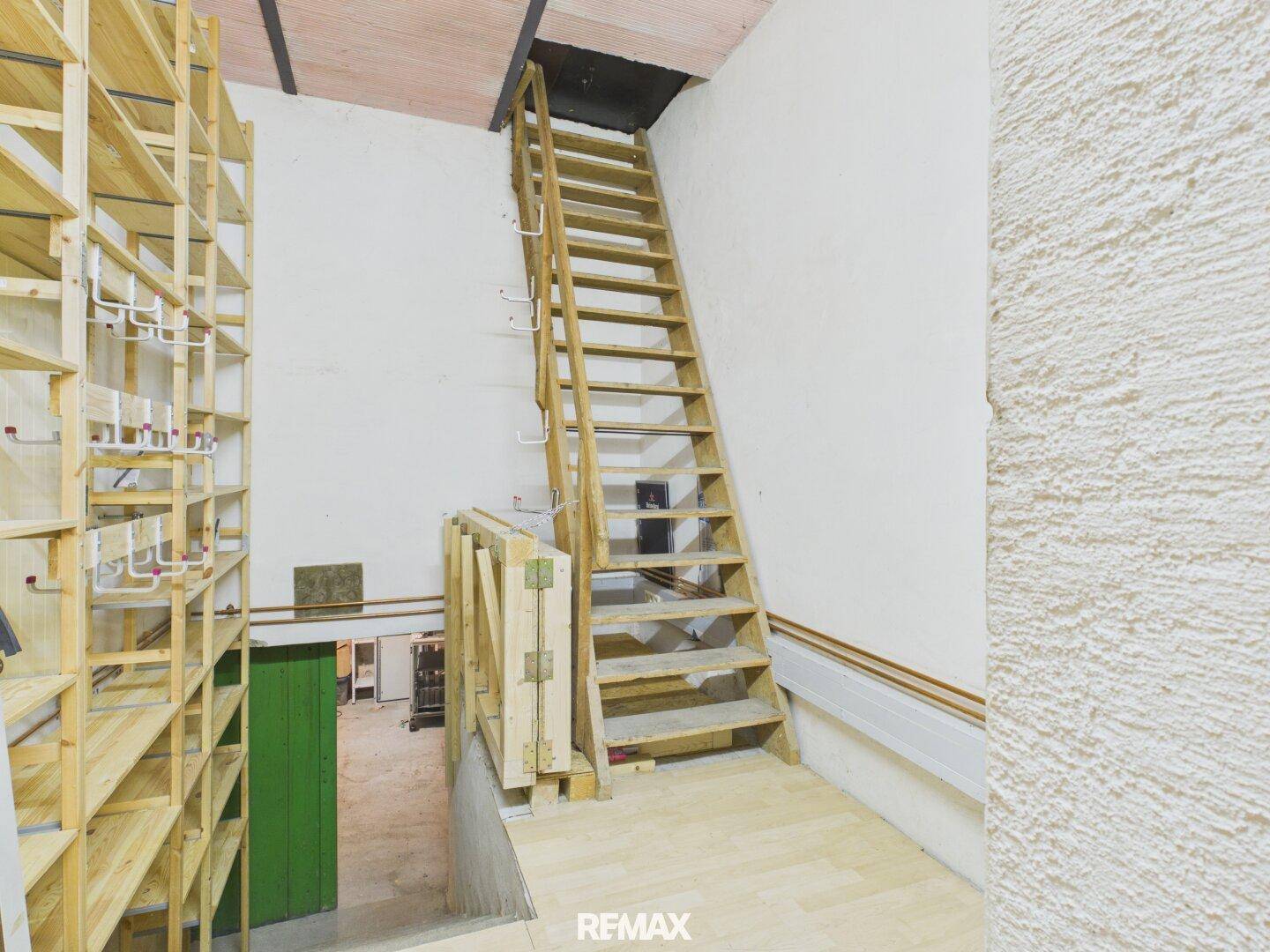 Dachboden mit Holztreppe, Regalen und unfertigen Wänden.