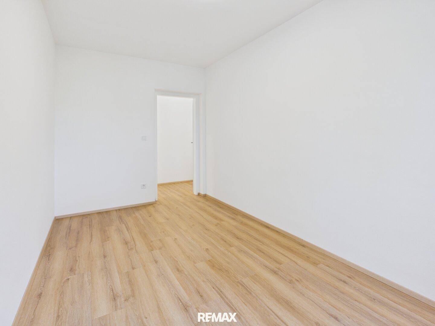 Geräumiges Zimmer mit Laminatboden und weißen Wänden, ideal als Kinder- oder Gästezimmer.