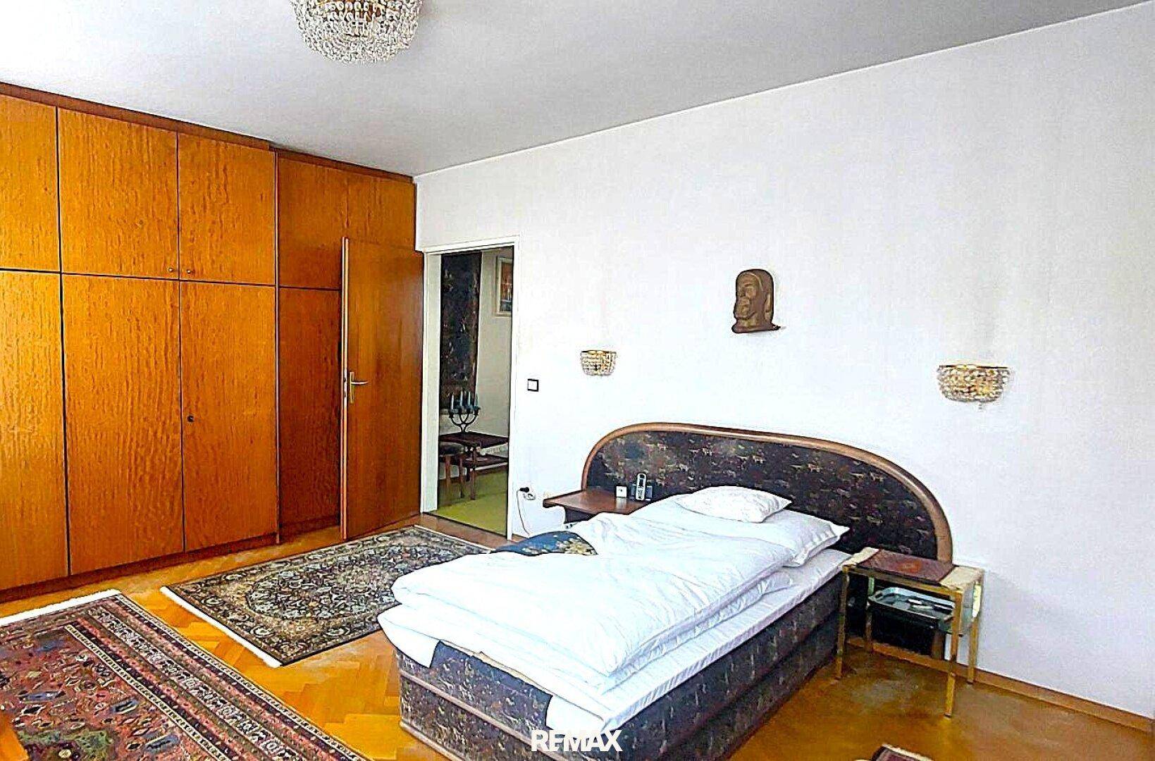 Helles Schlafzimmer mit Doppelbett, großen Holzschränken und einem gemusterten Teppichboden.