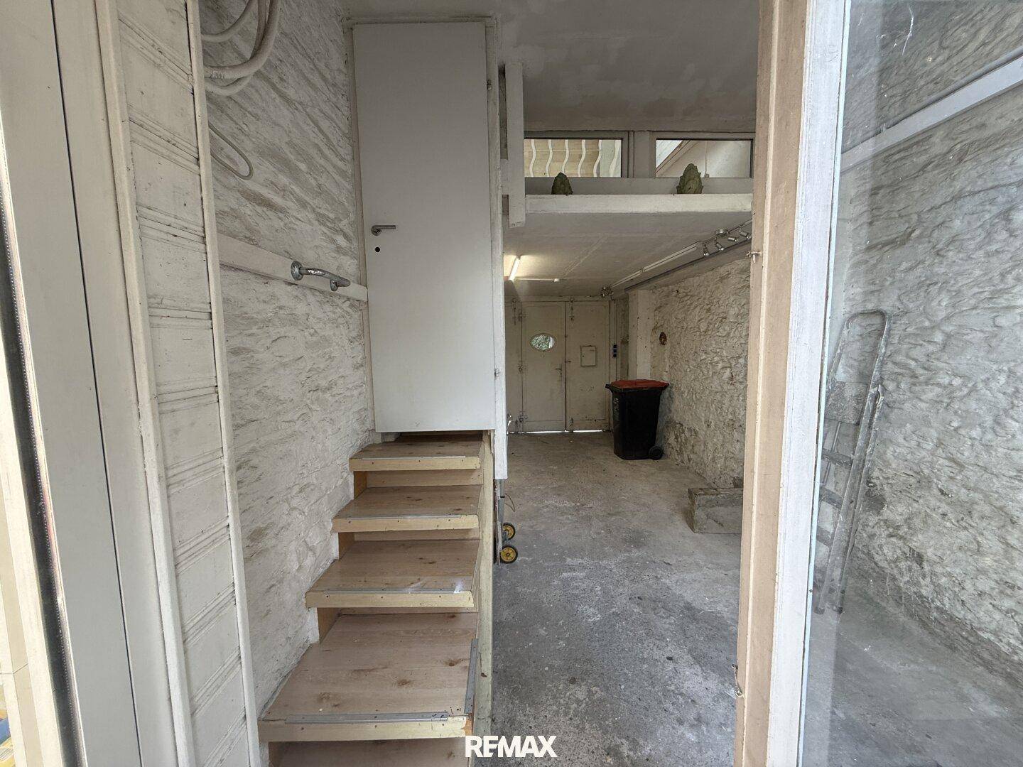 Unfertiger Kellerraum mit Betonelementen, einer Holztreppe und Lagerfläche.