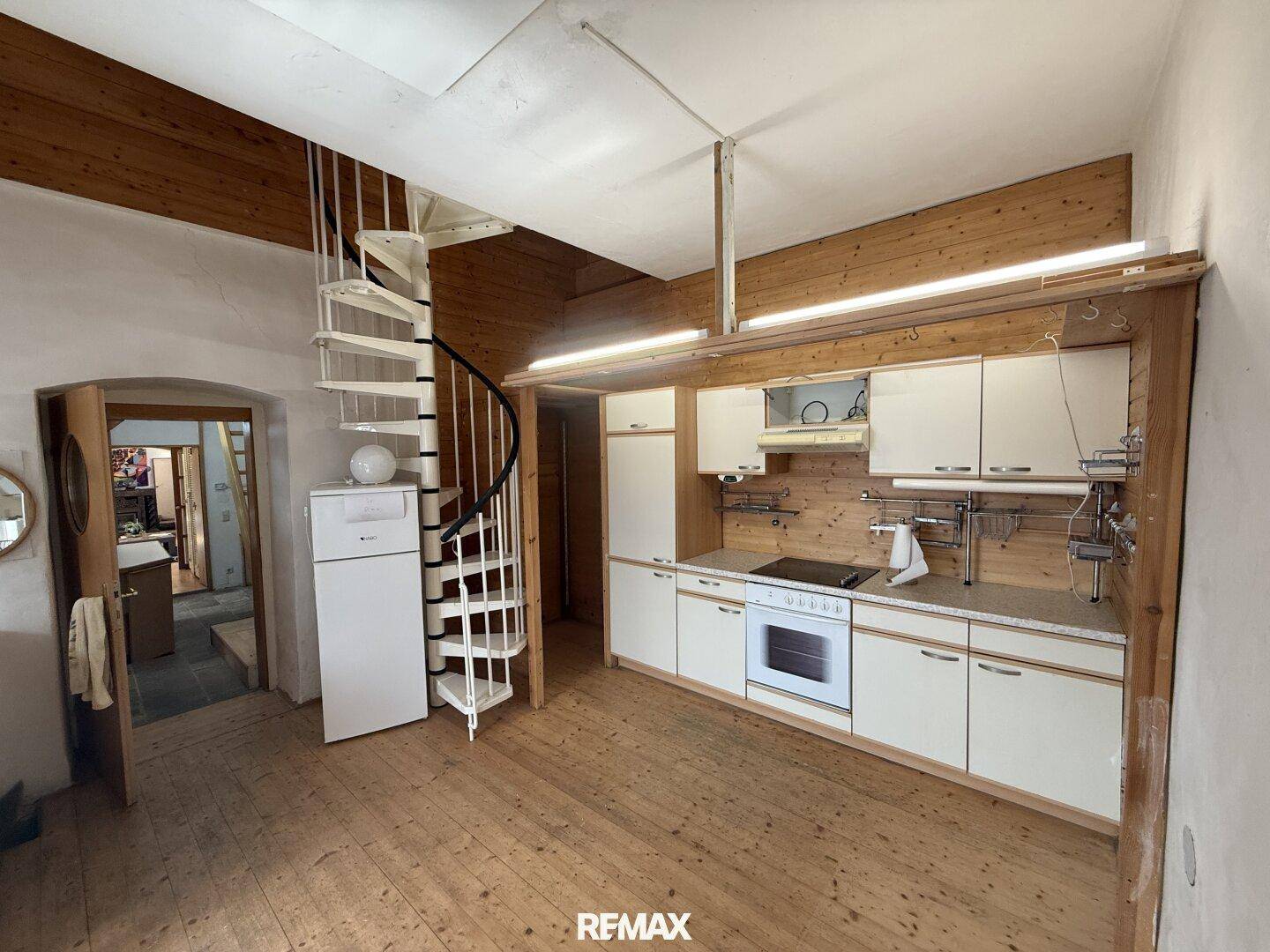 Rustikale Küche mit Holzdecken, Einbauschränken und einer Wendeltreppe zum Obergeschoss.
