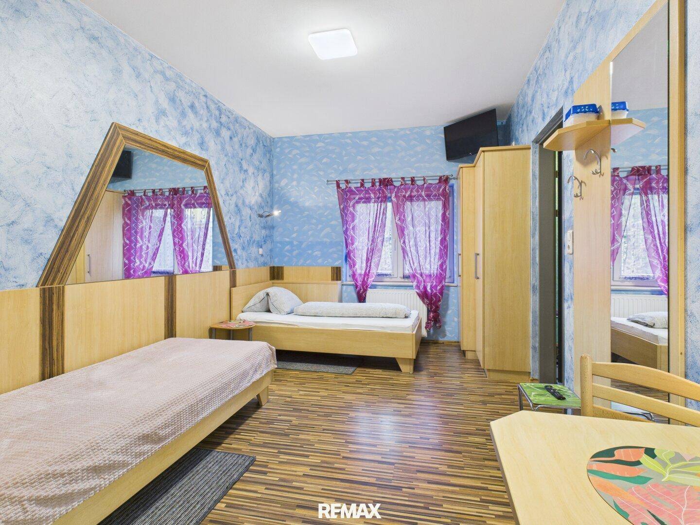Schlafzimmer mit zwei Betten, Laminatboden und blauer Wandgestaltung, bietet eine gemütliche Atmosphäre.