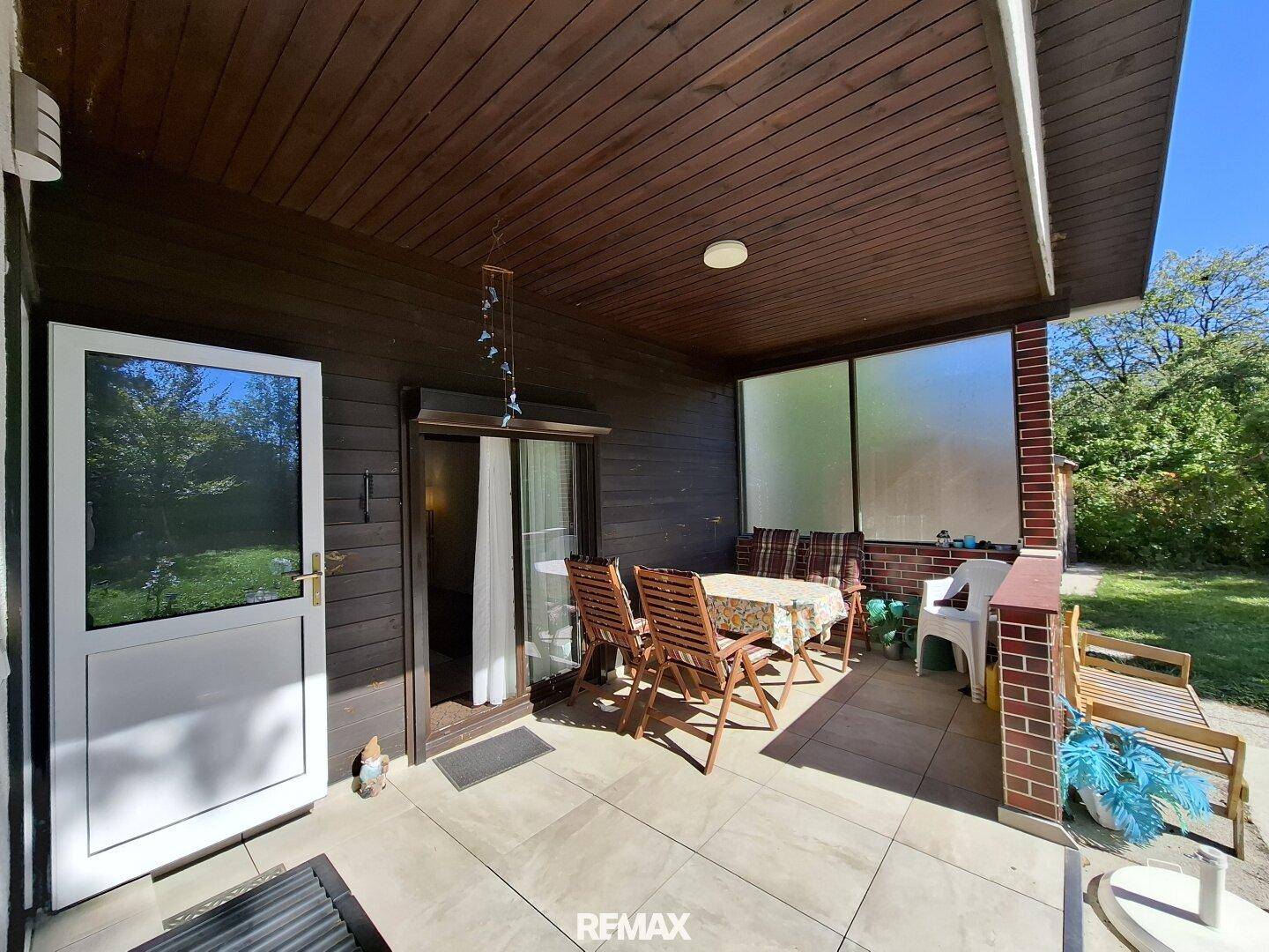 Überdachte Terrasse mit Holztisch und Stühlen, ideal für entspannte Stunden im Freien.
