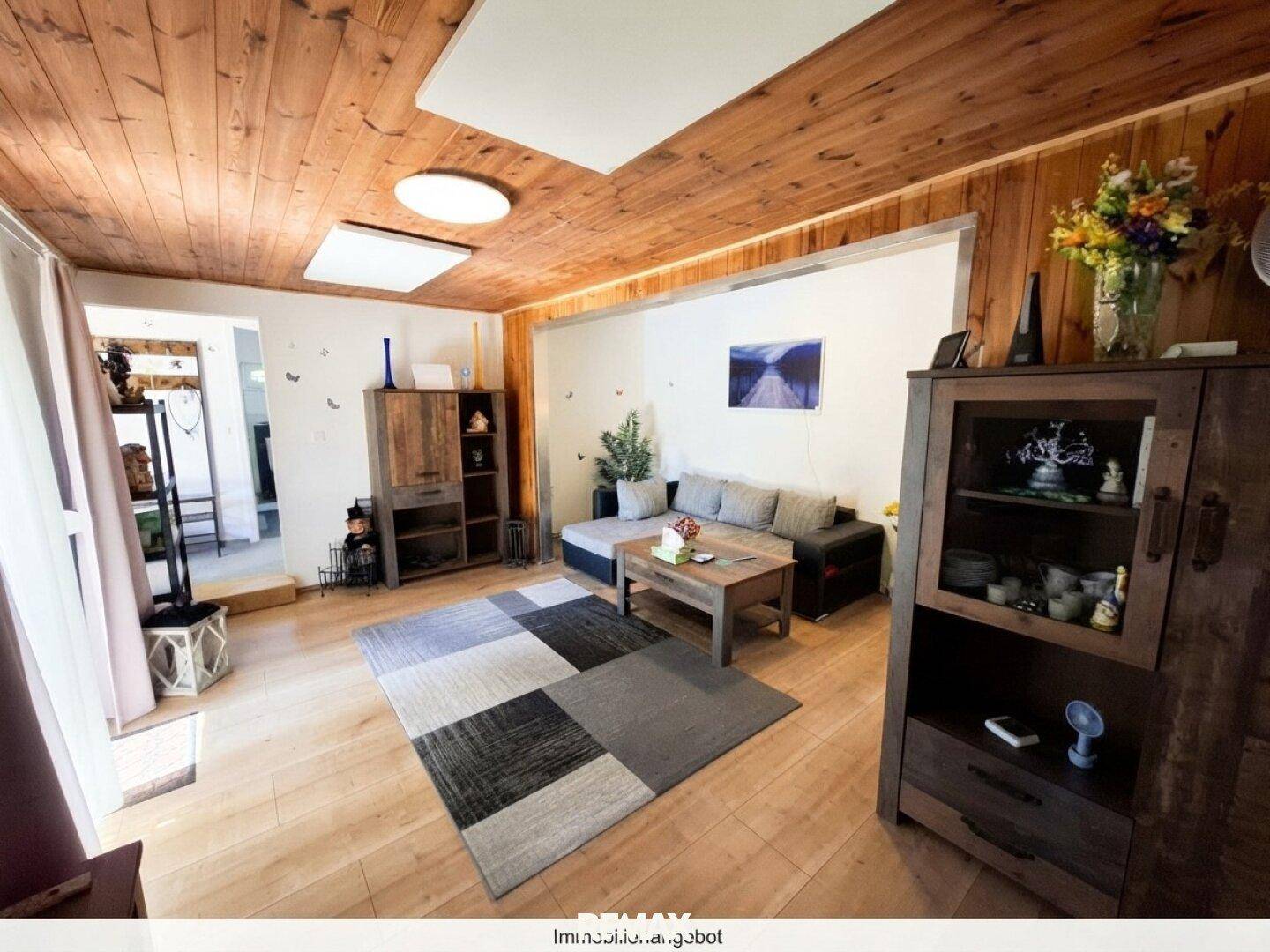 Geräumiges Wohnzimmer mit Holzbalkendecke, Parkettboden und moderner Einrichtung.