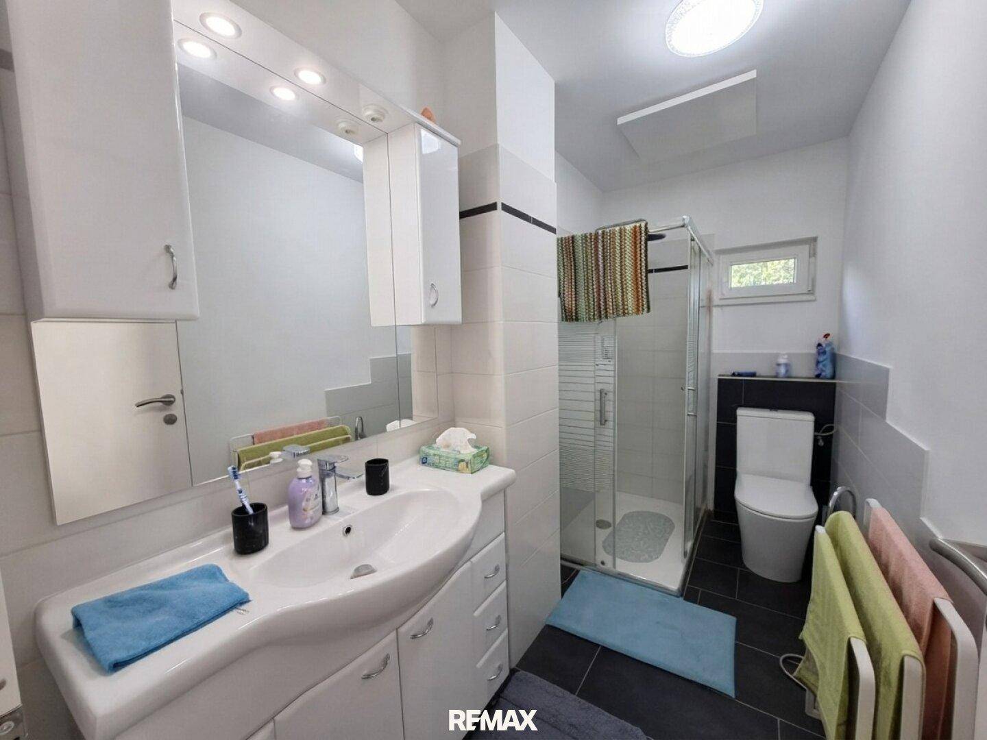 Modernes Badezimmer mit Dusche, Einzelwaschbecken und Fenster.