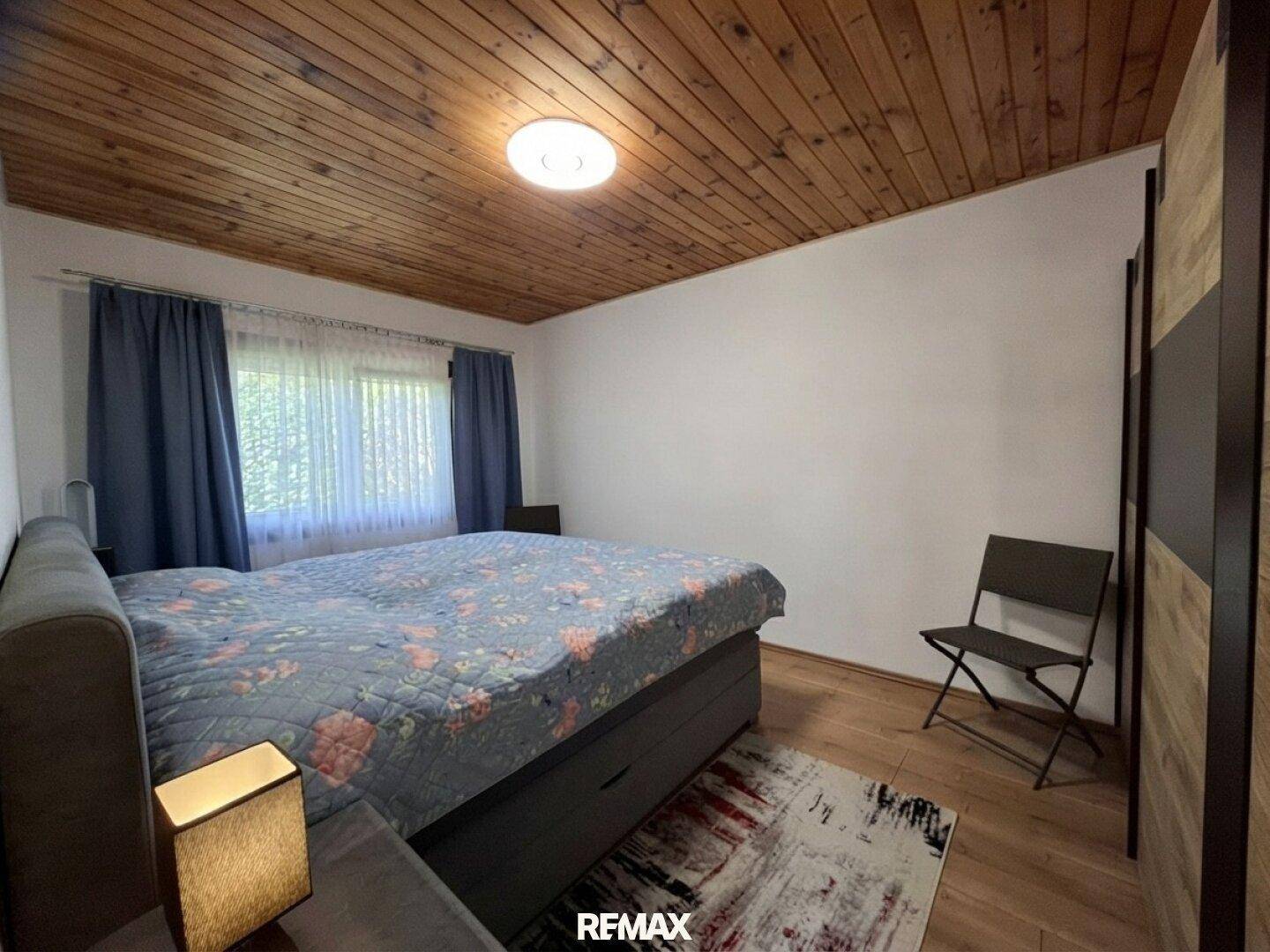 Gemütliches Schlafzimmer mit Holzbalkendecke, Parkettboden und großem Bett.