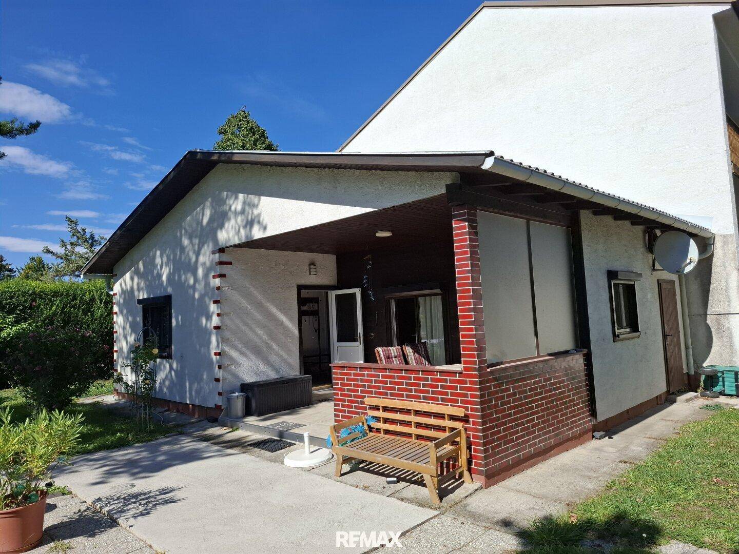 Seitenansicht des Hauses mit überdachter Terrasse und Gartenbereich.