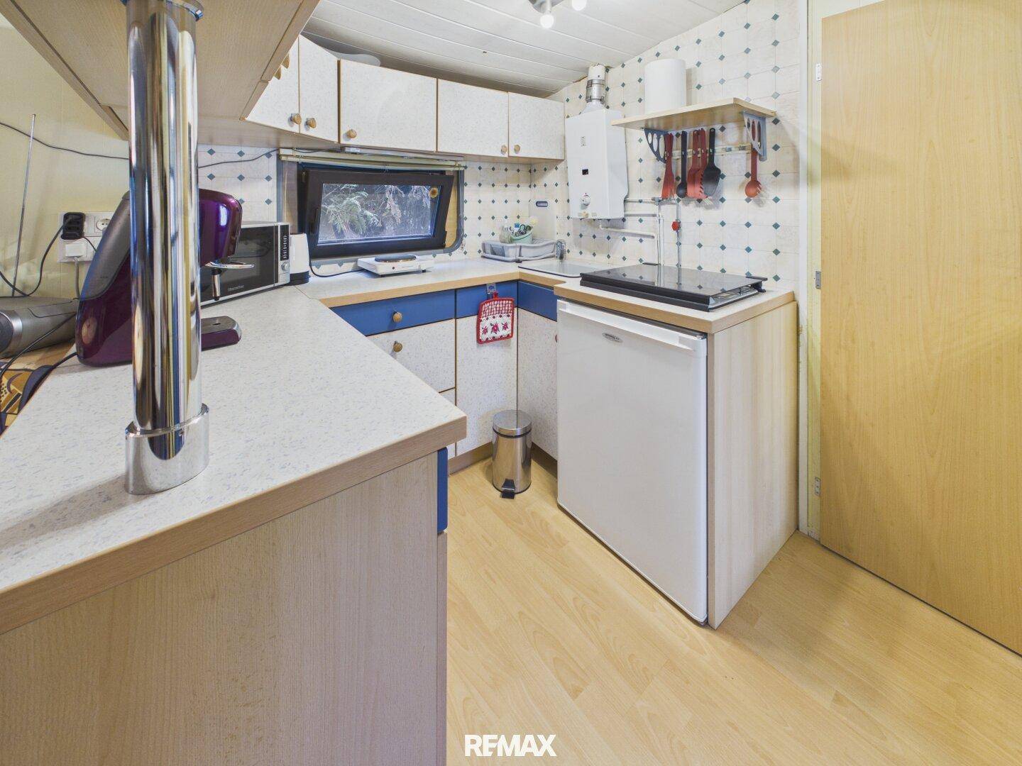 Funktionale kleine Küche mit Kühlschrank, Mikrowelle und Gasherd.