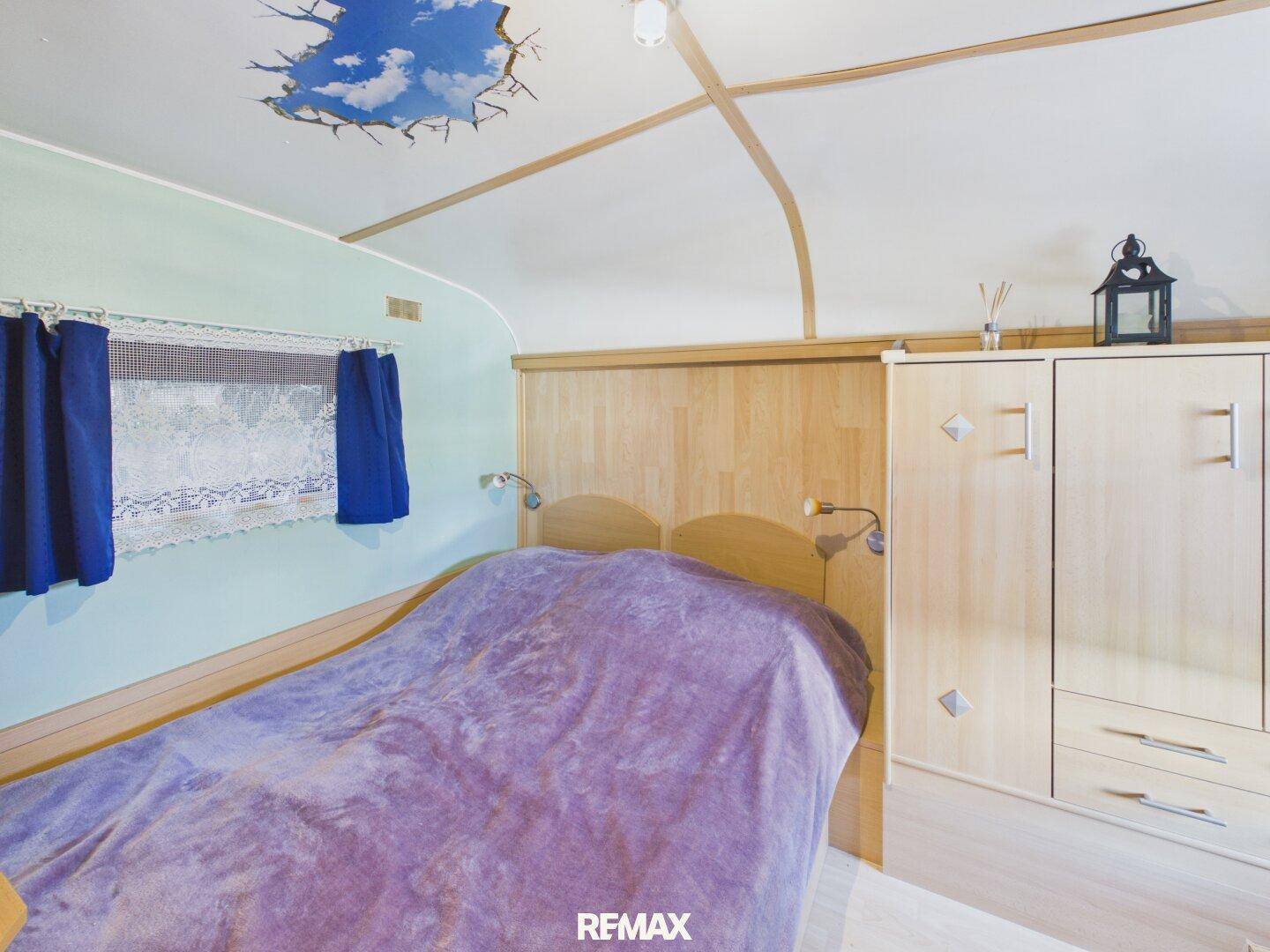 Gemütliches Schlafzimmer mit Holzbett, Kleiderschrank und Deckenbemalung.