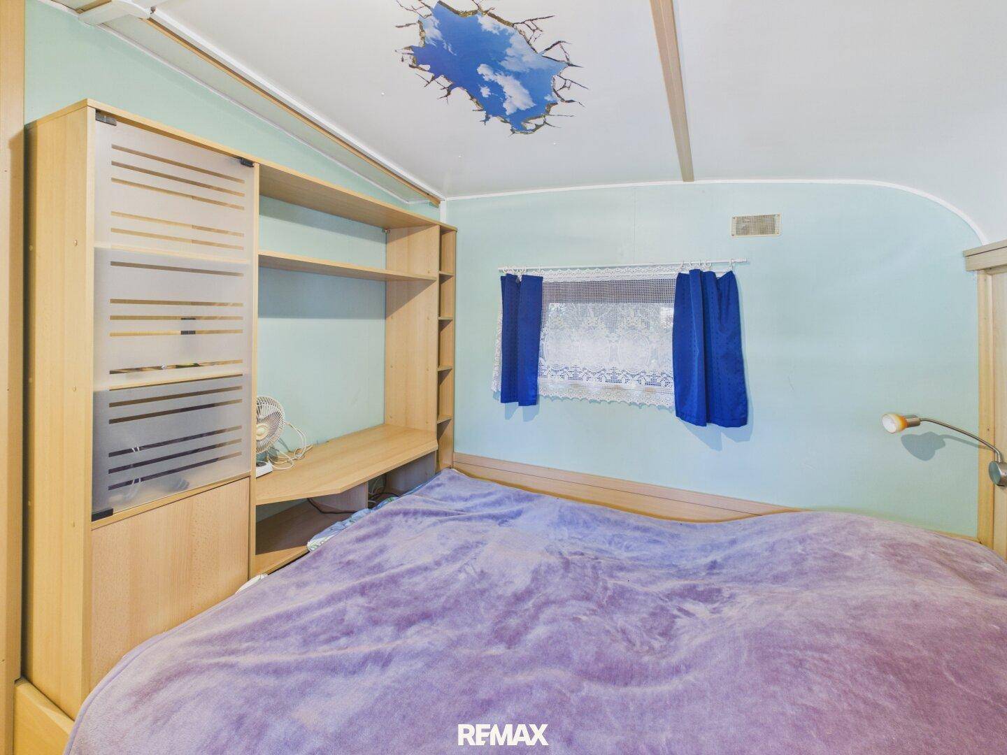Schlafzimmer mit Doppelbett, Holzmöbeln und einer kreativen Deckenbemalung.