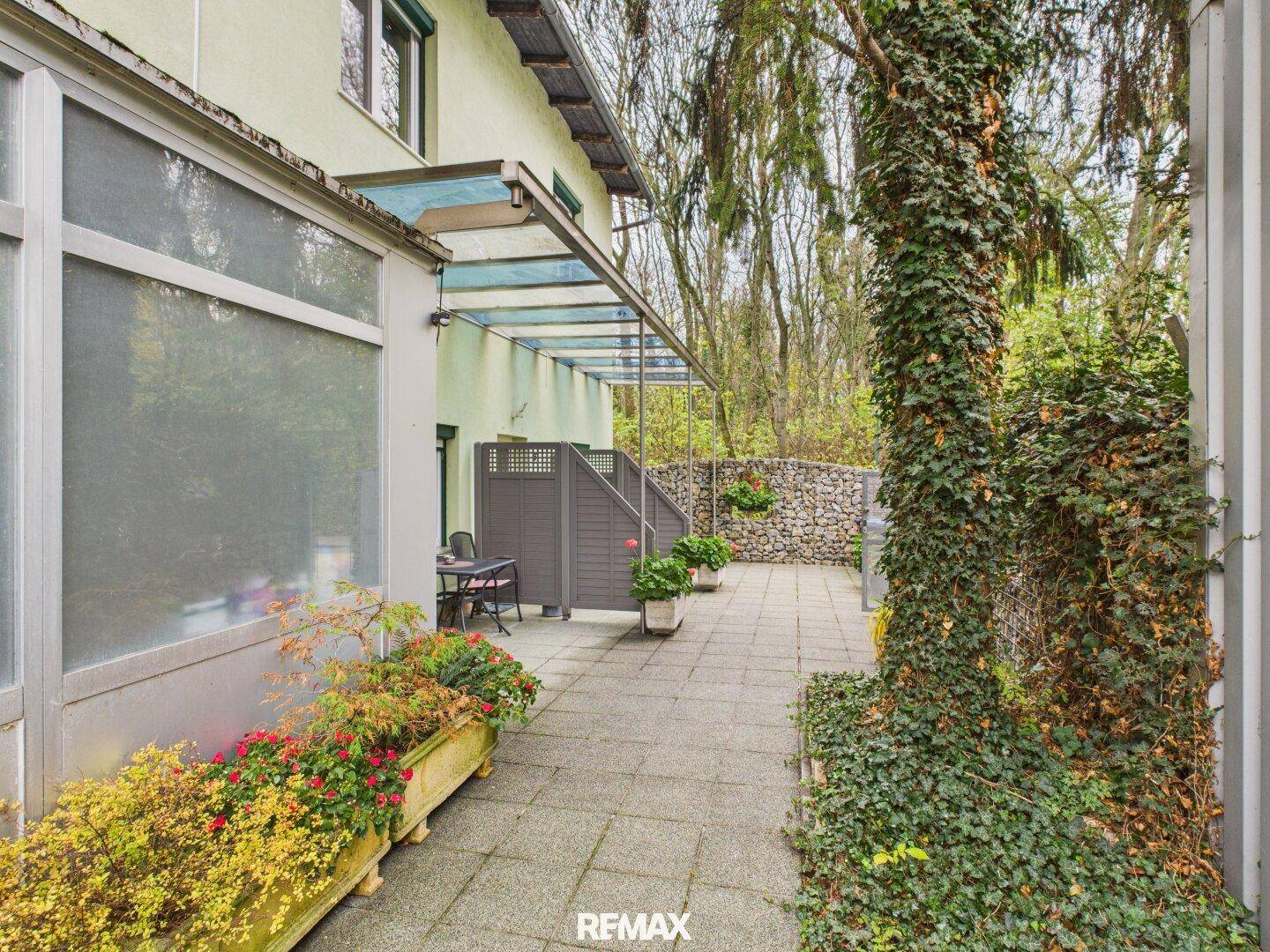 Überdachte Terrasse mit Sitzgelegenheiten und Blick ins Grüne, ideal für entspannte Stunden im Freien.