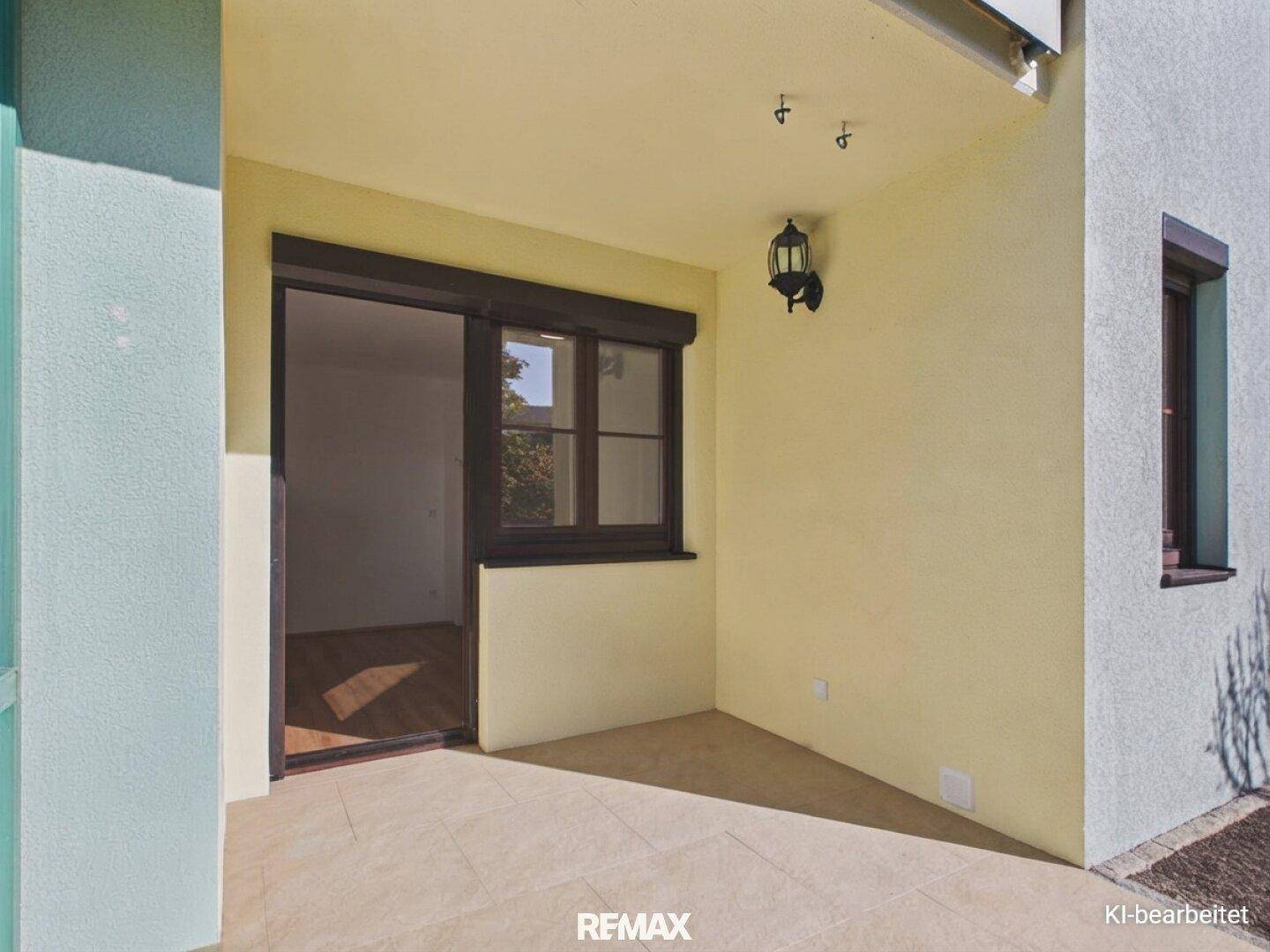 Helle, überdachte Loggia mit Fliesenboden und direktem Zugang zu einem Innenraum.