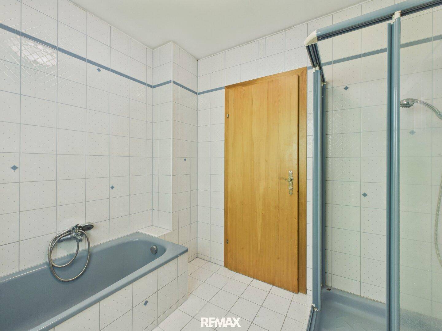 Badezimmer mit blauen Fliesen, Badewanne und Duschkabine, typisch für die 80er Jahre.