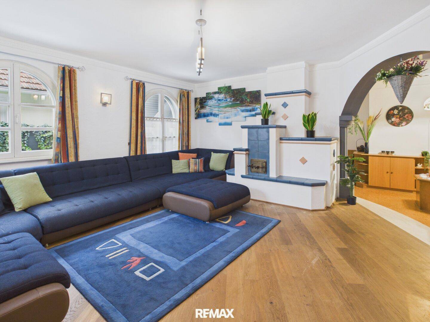 Gemütliches Wohnzimmer mit großem Ecksofa, Kachelofen und Holzboden.