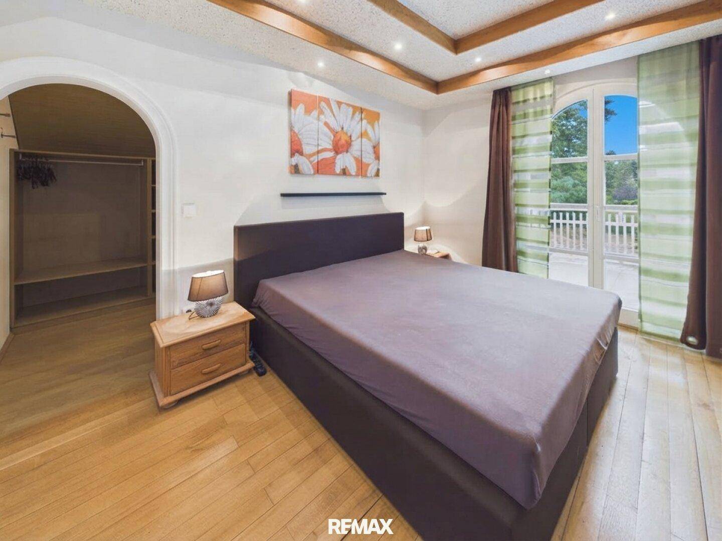 Schlafzimmer mit Doppelbett, Holzboden, Einbauschrank und Zugang zum Balkon.