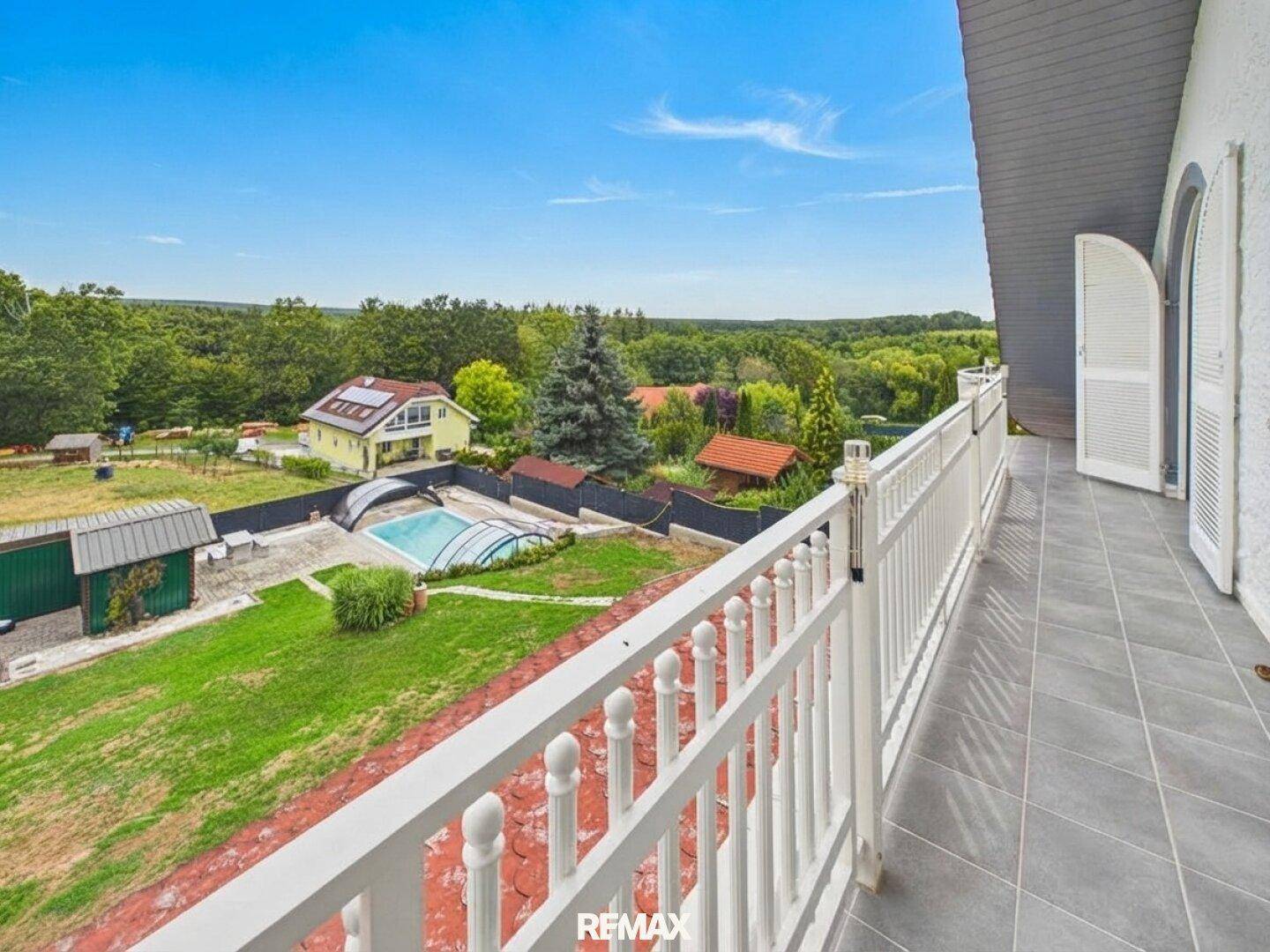 Langer Balkon mit weitem Blick über die grüne Landschaft und das Anwesen.