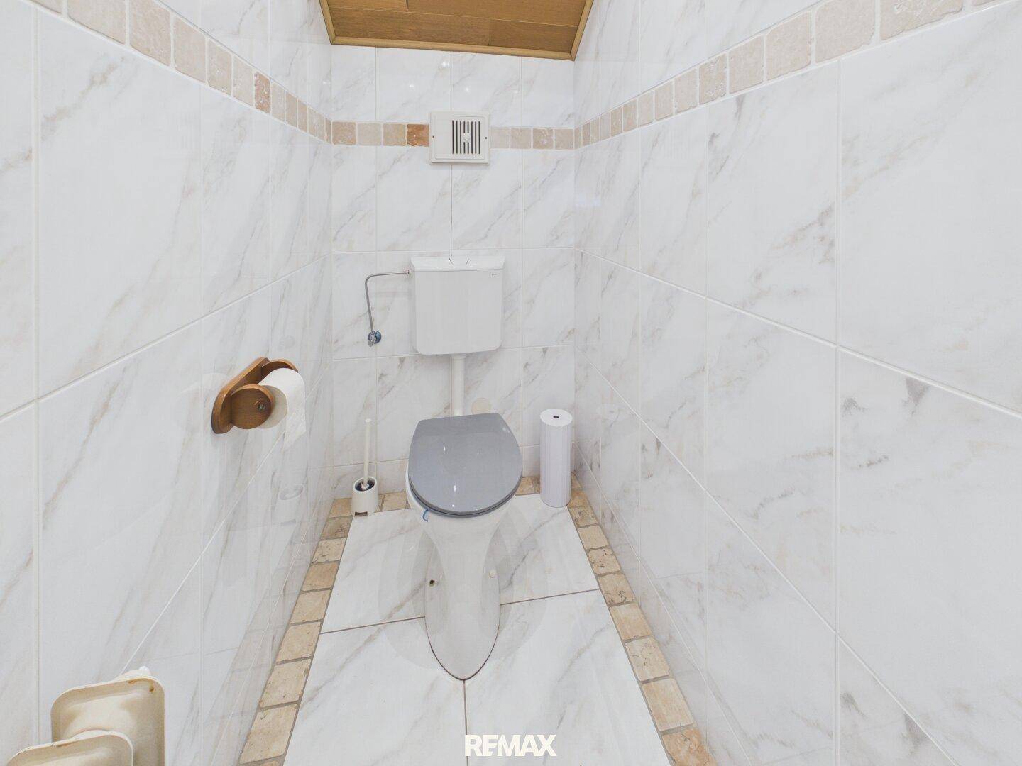 Separates WC mit Marmorfliesen und Lüftungssystem.