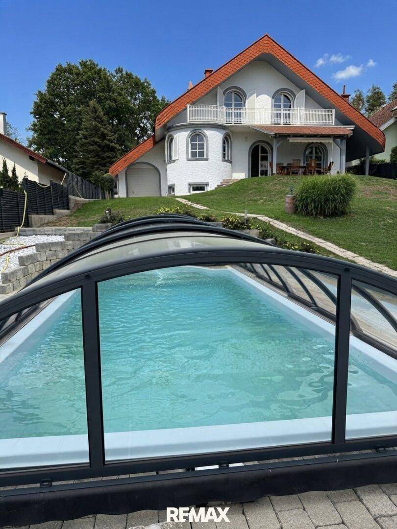 Außenpool mit Überdachung und Blick auf das Wohnhaus in sonniger Lage.