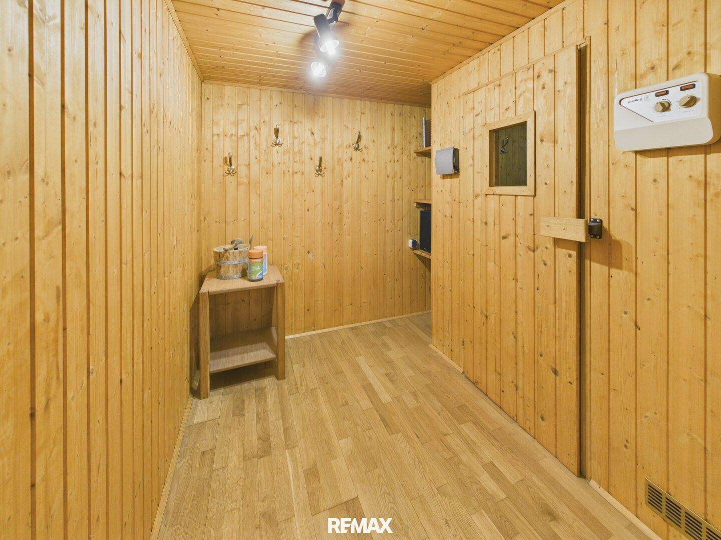 Heller Vorraum mit Holzvertäfelung und Ablagetisch, der zu einer Sauna führt.
