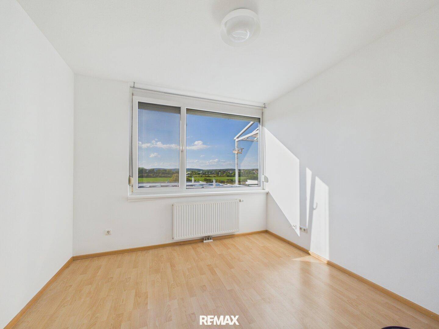 Lichtdurchflutetes Zimmer mit Parkettboden und weitem Blick ins Grüne, ideal für ein Schlafzimmer.
