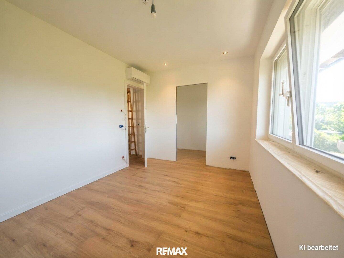 Helles Schlafzimmer mit Holz-Look-Boden, großem Fenster und Klimaanlage für angenehmes Raumklima.