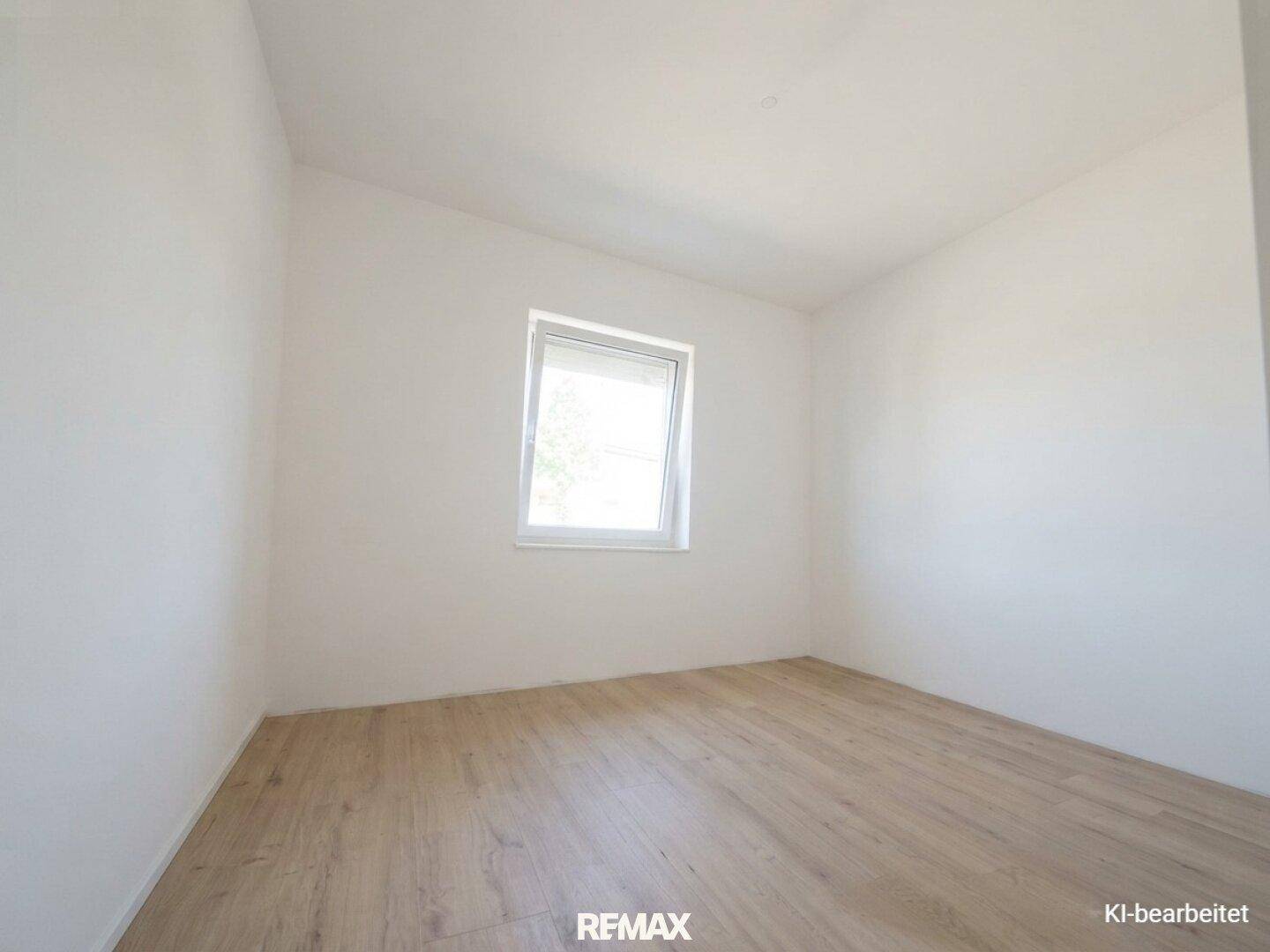 Helles, leeres Zimmer mit Holz-Look-Boden und einem Fenster, bereit zur individuellen Gestaltung.