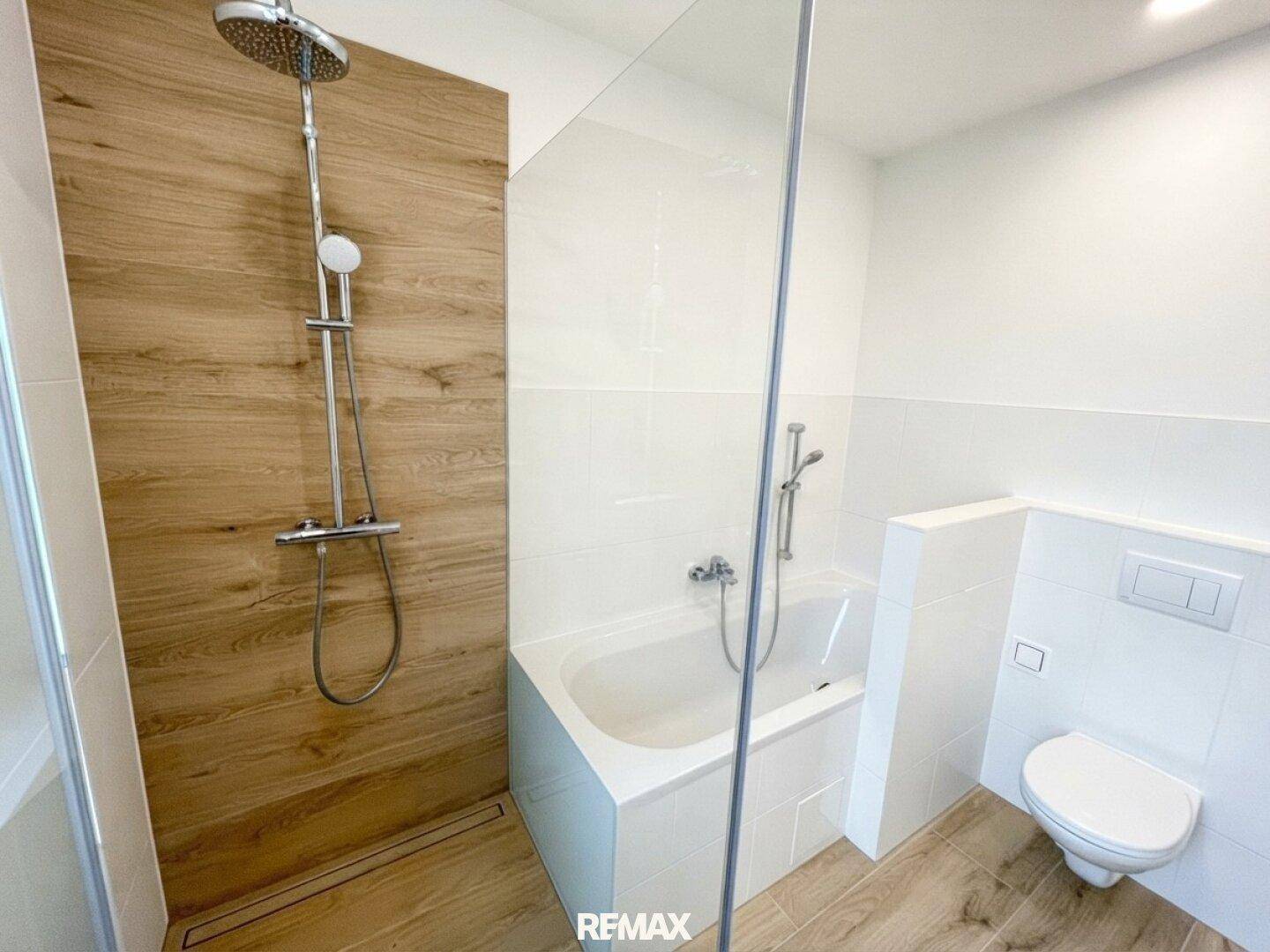 Modernes Badezimmer mit begehbarer Dusche, Badewanne und wandhängendem WC, elegant gefliest.