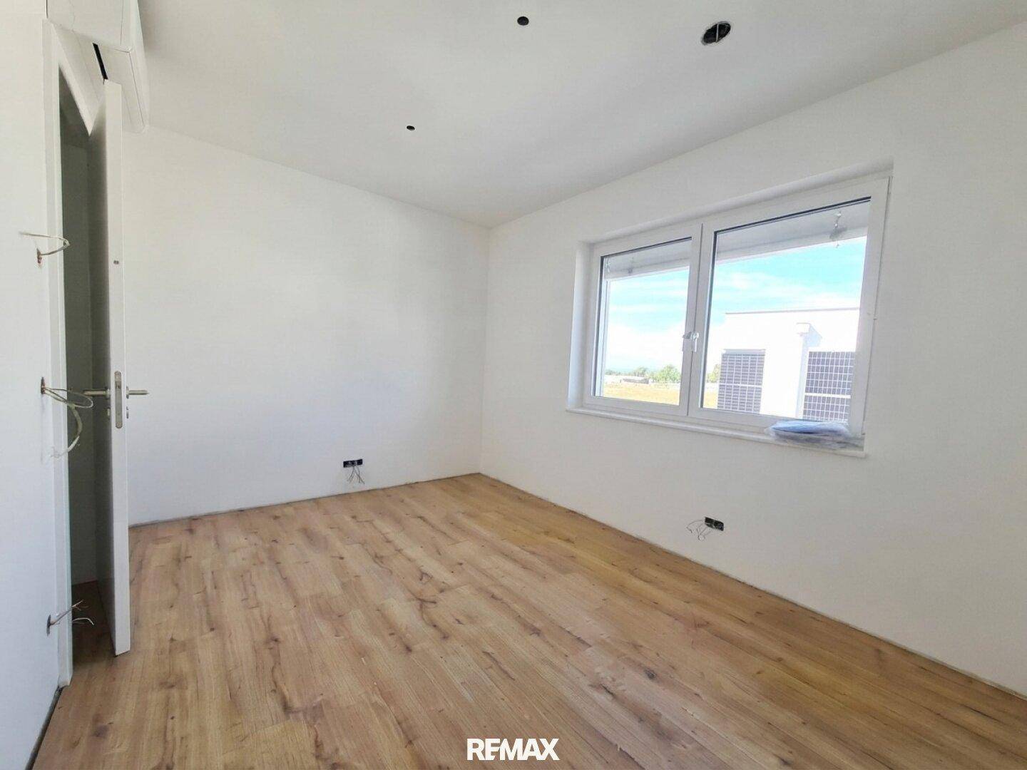Geräumiges Schlafzimmer mit Holz-Look-Boden und einem Fenster, das den Raum mit Licht füllt.