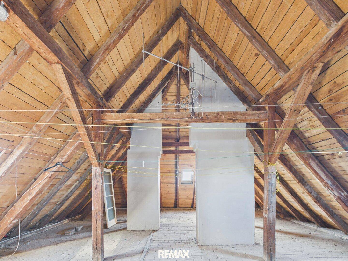 Geräumiger Dachboden mit sichtbaren Holzbalken und Holzverkleidung, bereit zum Ausbau.