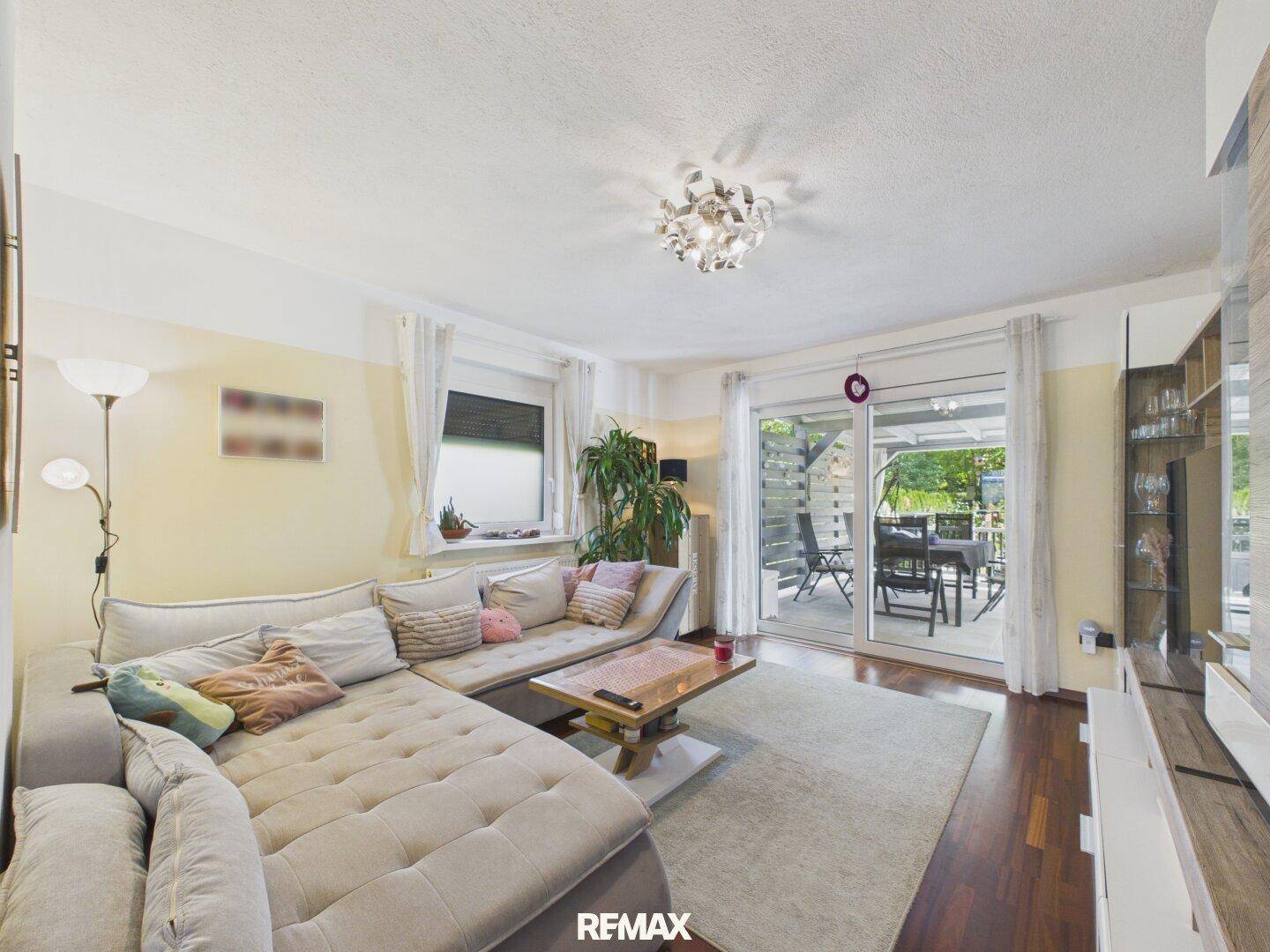 Gemütliches Wohnzimmer mit großem Ecksofa, Holzboden und Zugang zur Terrasse.