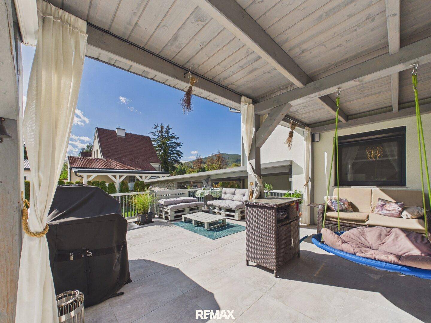 Geräumige überdachte Terrasse mit bequemen Sitzgelegenheiten und Blick auf die Umgebung.