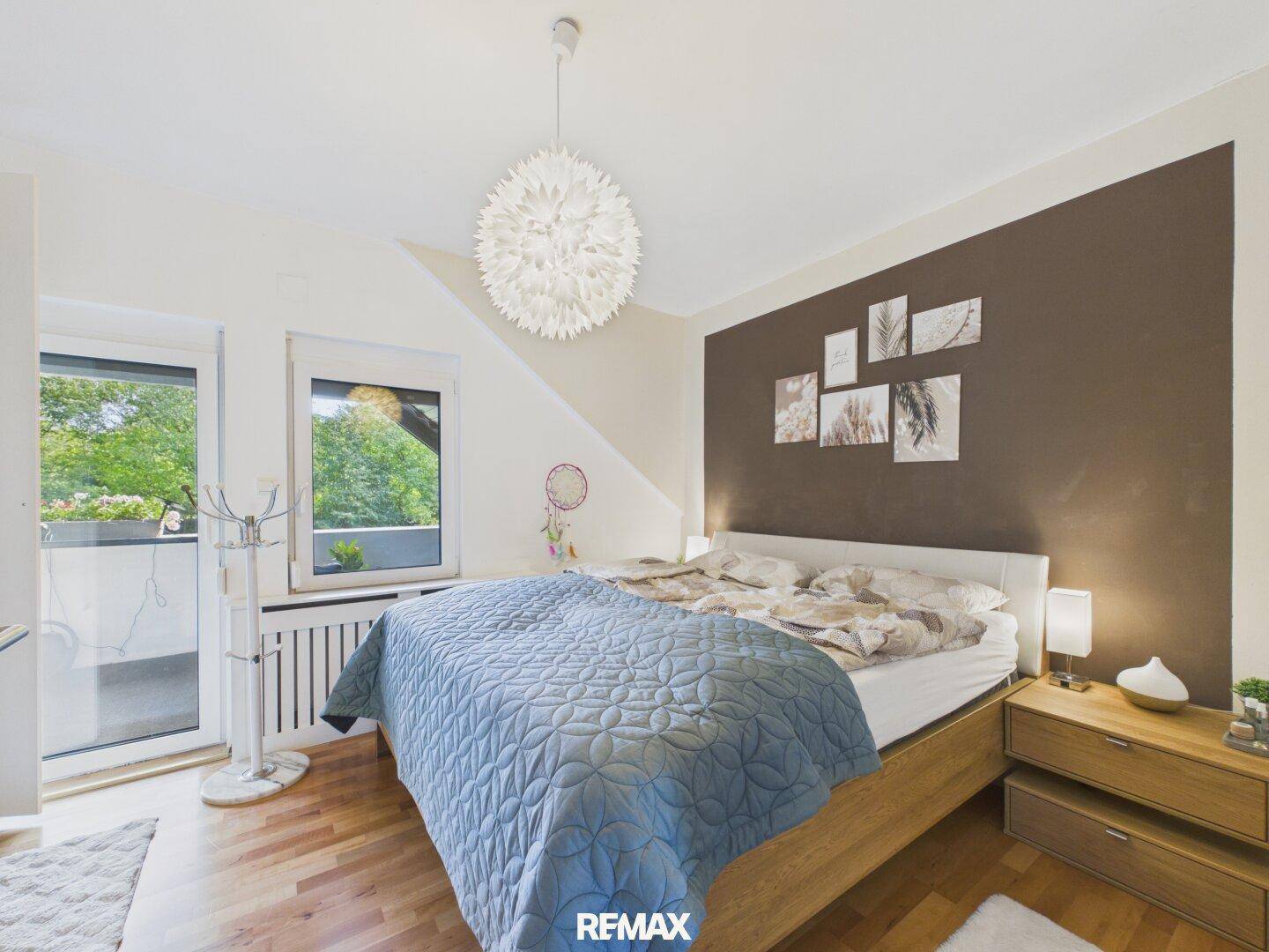 Gemütliches Schlafzimmer mit Holzboden, Balkonzugang und dekorativer Wandgestaltung.