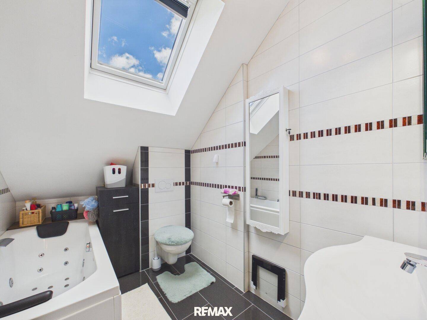 Modernes Badezimmer im Dachgeschoss mit Whirlpool, WC und Dachfenster.