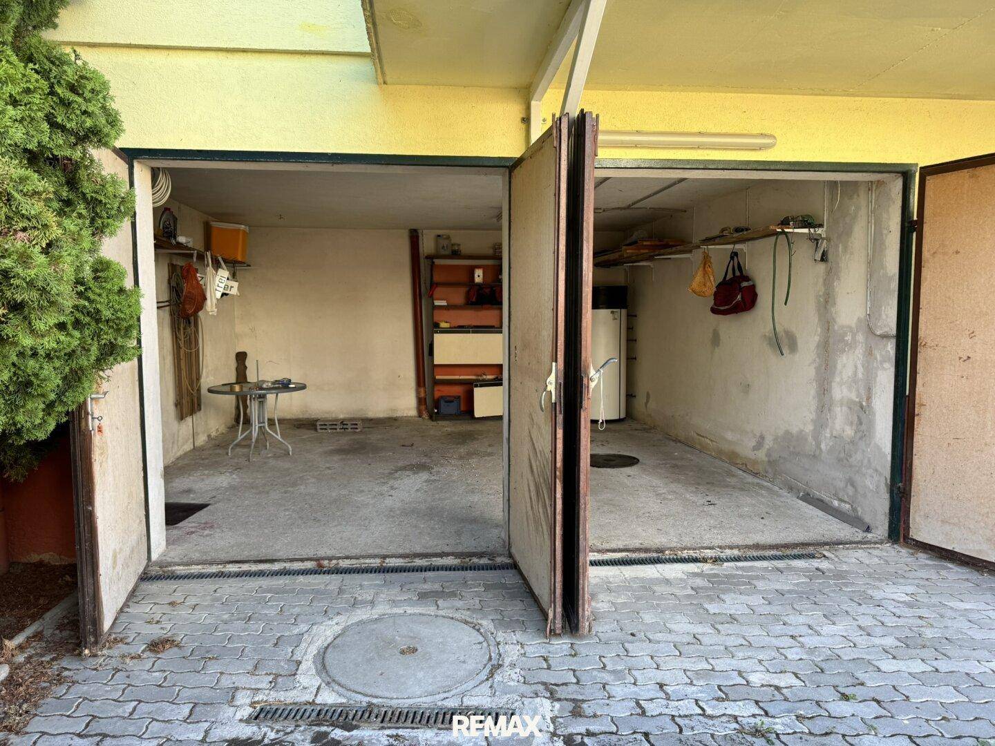 Offene Garagentore mit Blick in den Innenraum, der als Abstellraum genutzt wird.