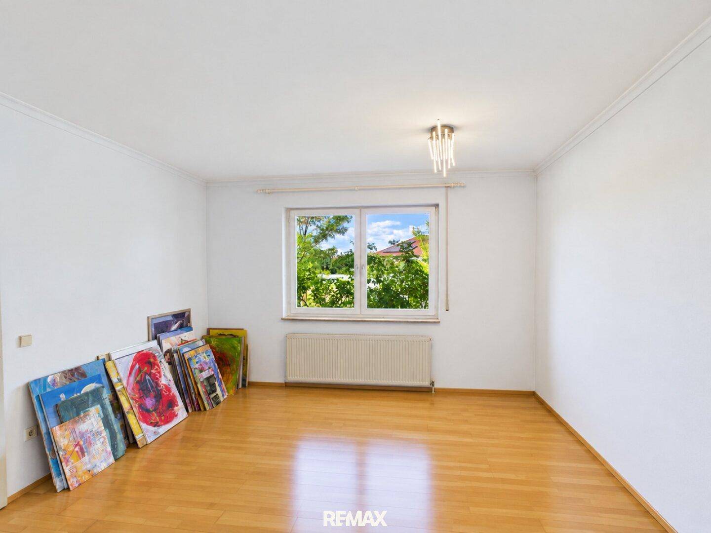 Heller Raum mit Parkettboden, großem Fenster und Heizkörper, derzeit als Atelier genutzt.