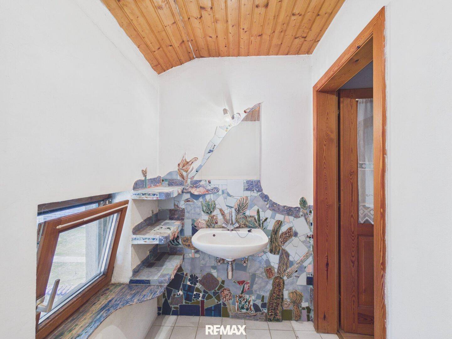 Originelles Badezimmer mit Mosaikfliesen, Holzdecke, Waschbecken und Fenster.