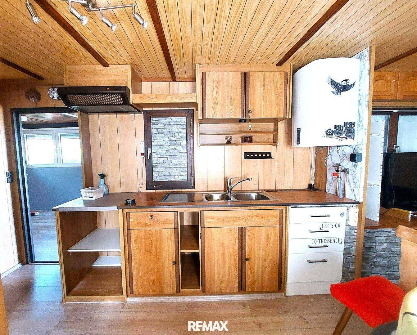 Rustikale Holzküche mit Doppelspüle, Dunstabzugshaube und Holzverkleidung an Wänden und Decke.