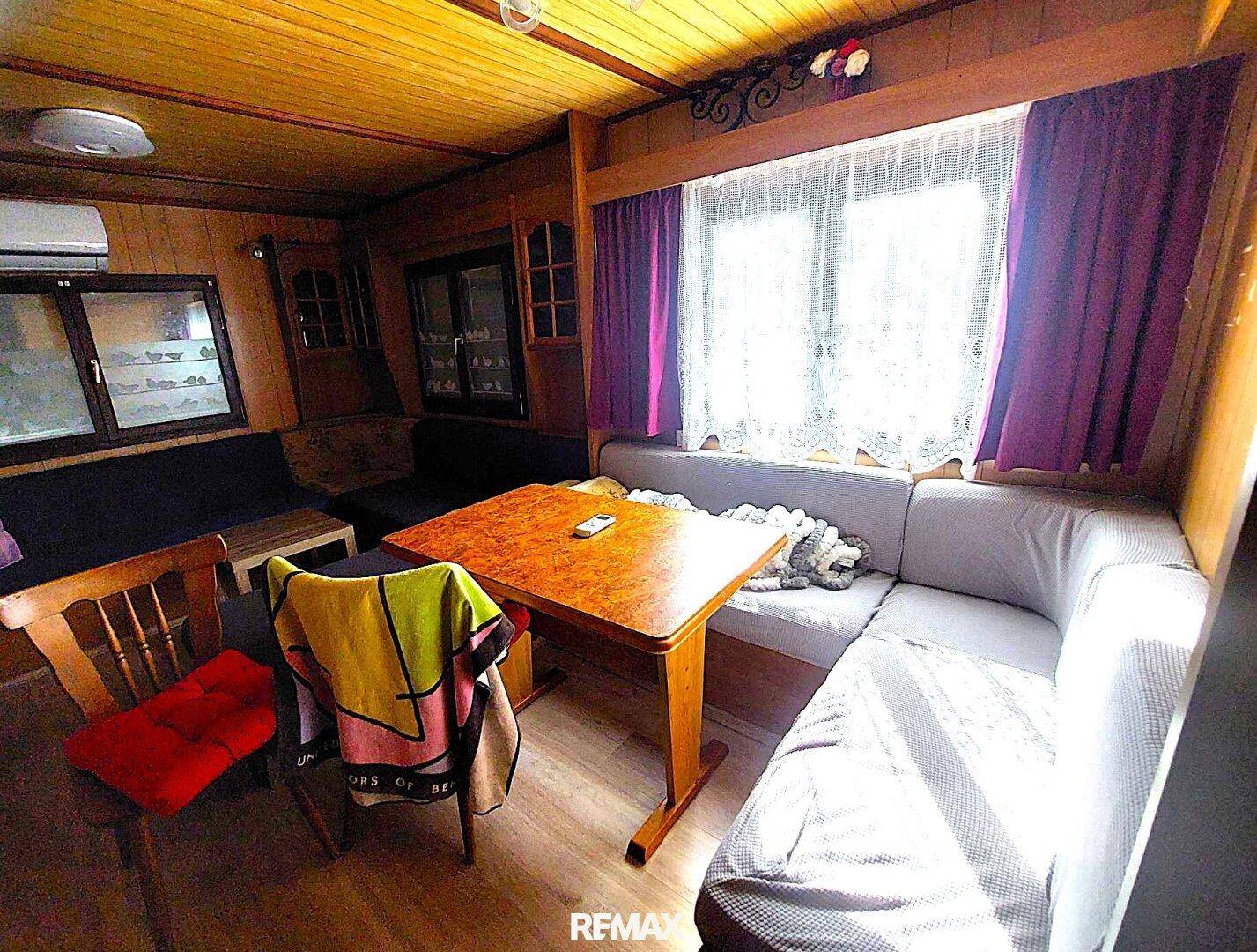 Wohn-Essbereich mit Holzwänden, Deckenverkleidung, Esstisch und Sitzbank.