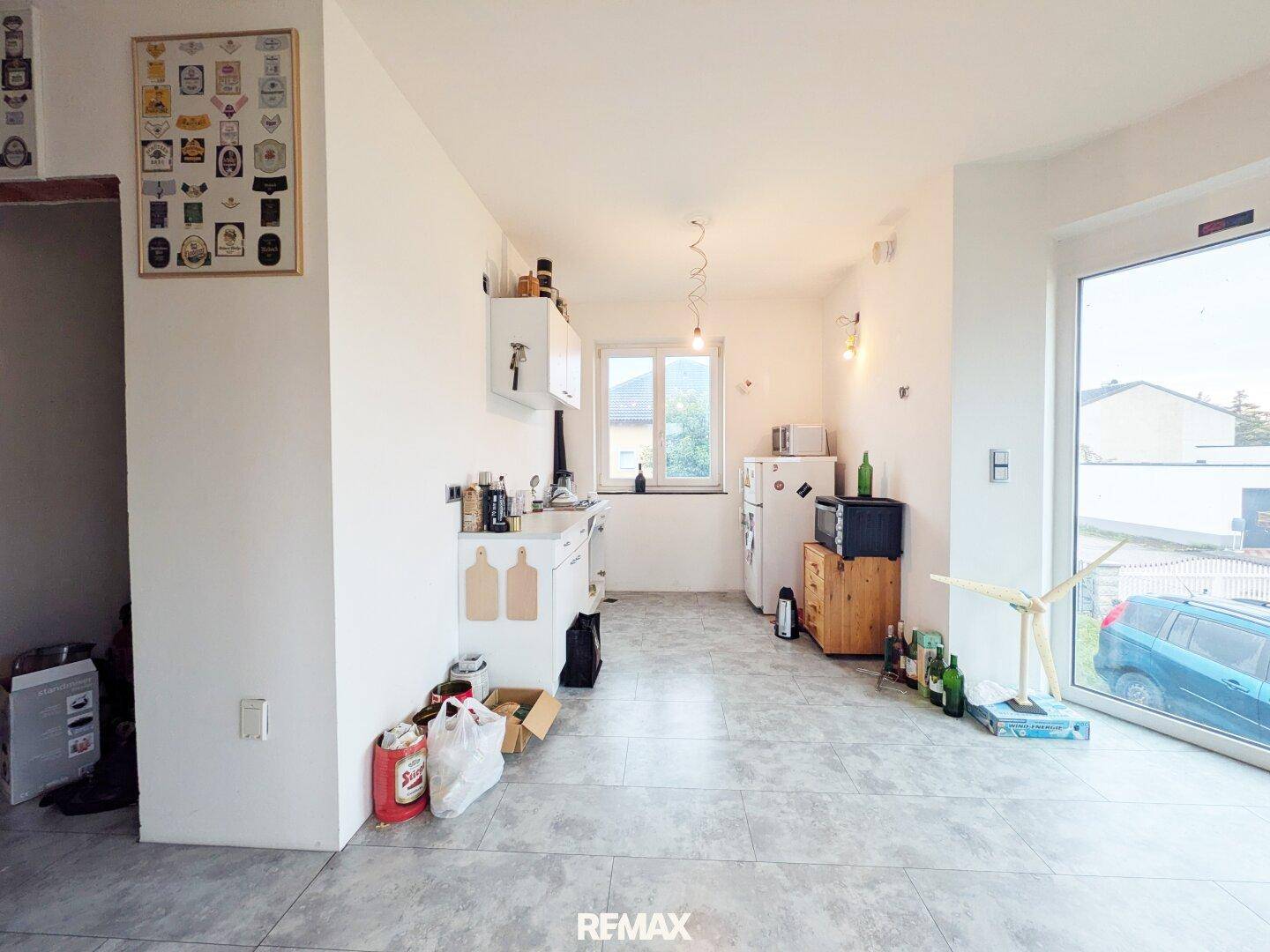 Helle Küche mit Fliesenboden, Fenster und Platz für eine moderne Einbauküche.