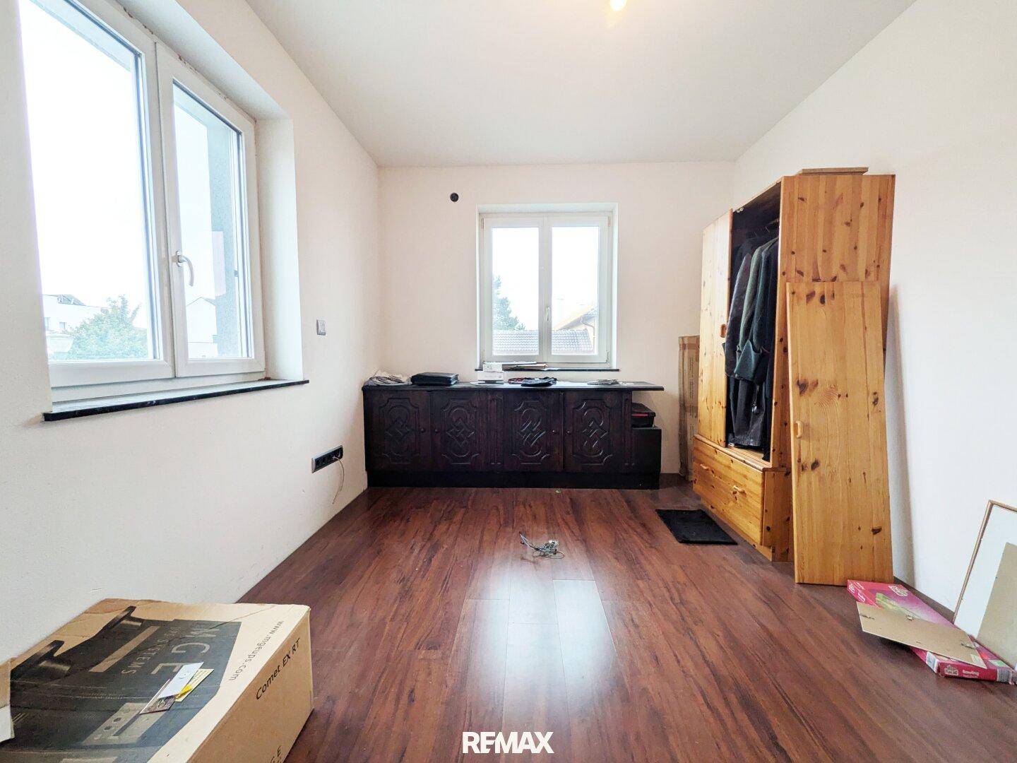 Helles Zimmer mit Holzboden und zwei Fenstern, ideal als Schlaf- oder Arbeitszimmer.