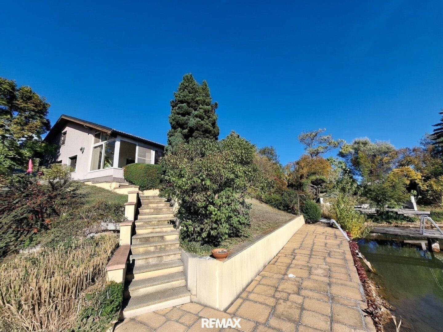 Außenansicht des Hauses mit Treppe zum Seeufer und gepflegter Gartenanlage.