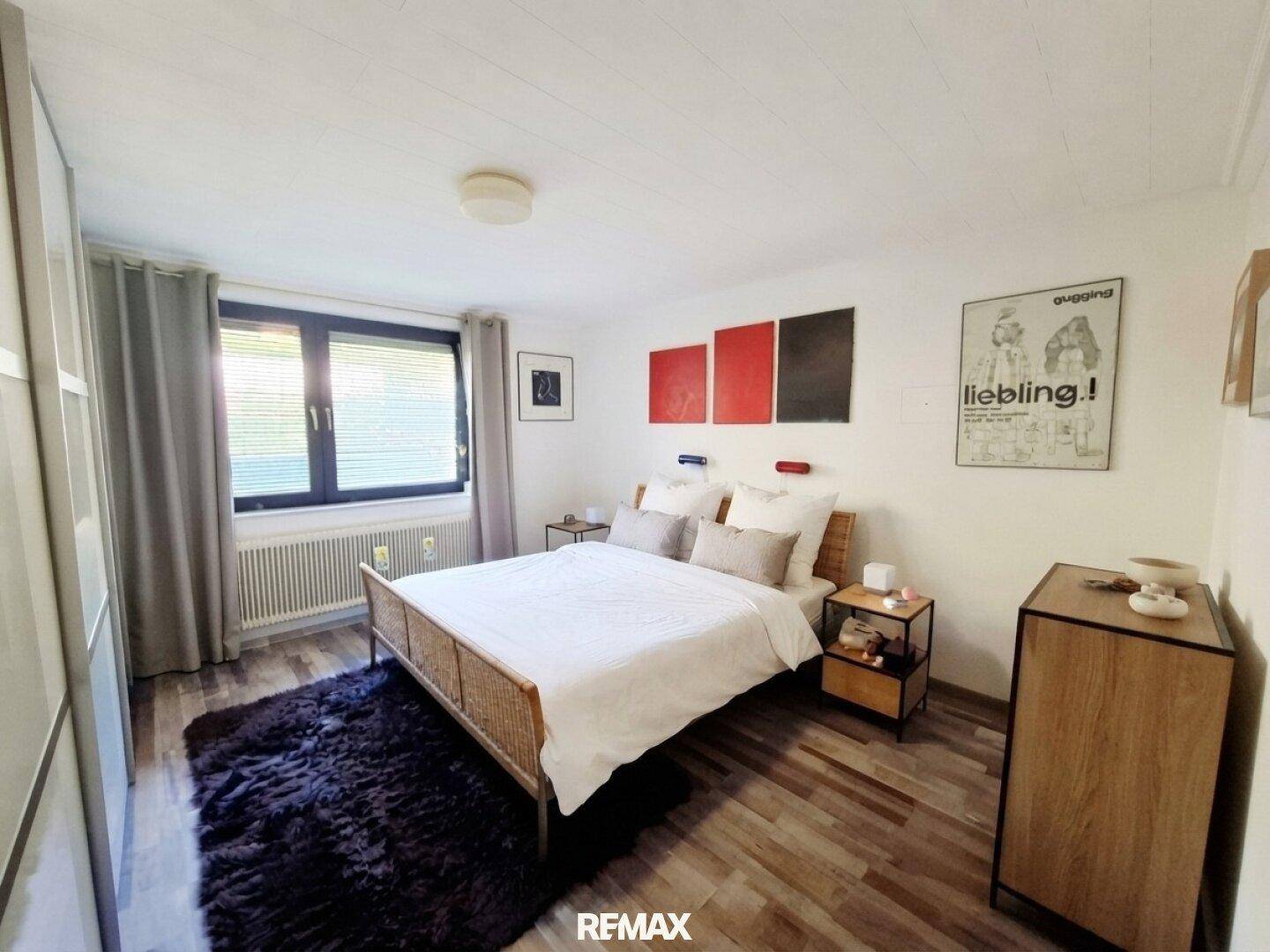 Schlafzimmer mit Holzboden, Doppelbett und Fenster mit Blick ins Grüne.