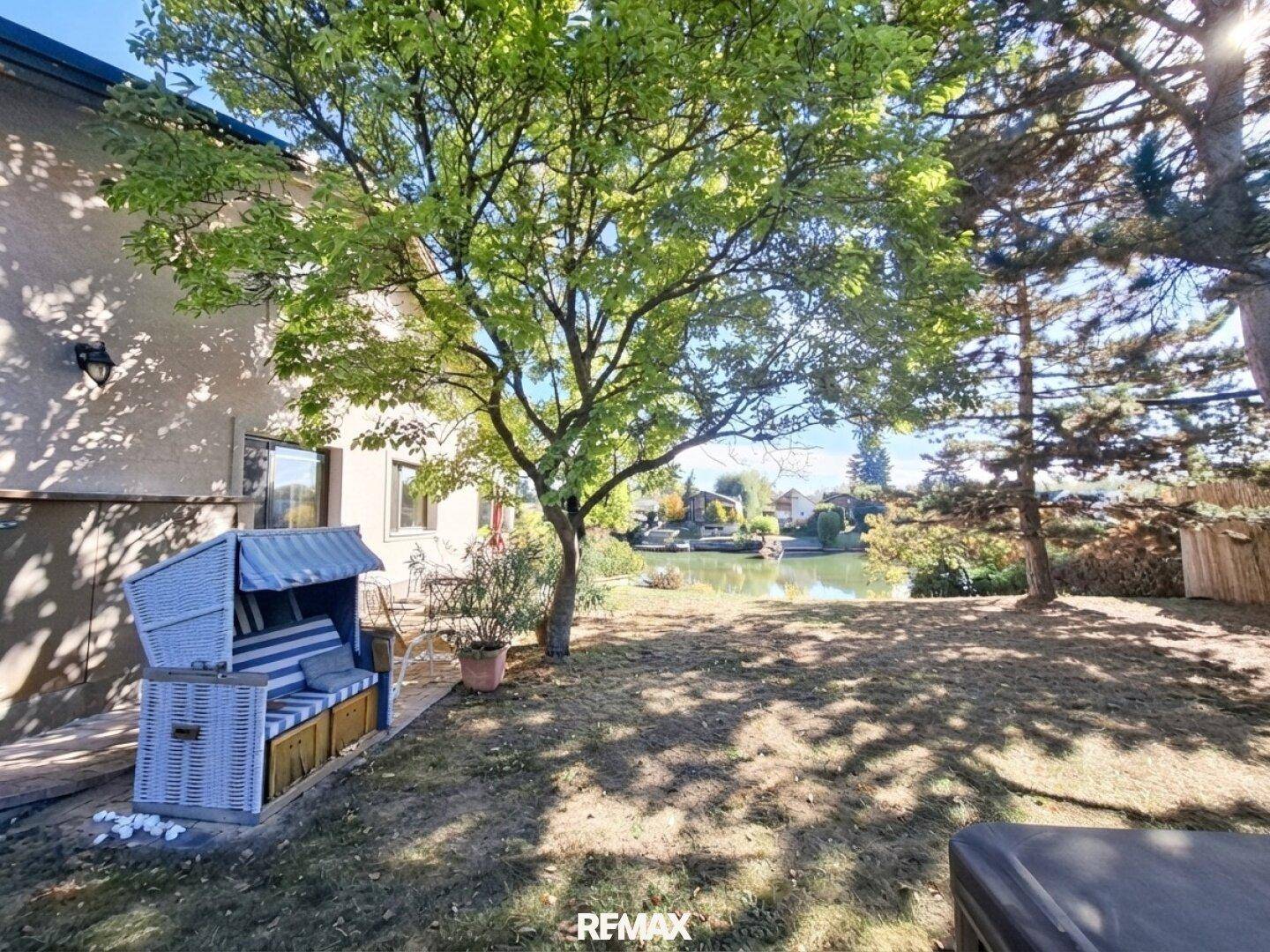 Gepflegter Garten mit Rasenfläche, Strandkorb und direktem Zugang zum See.