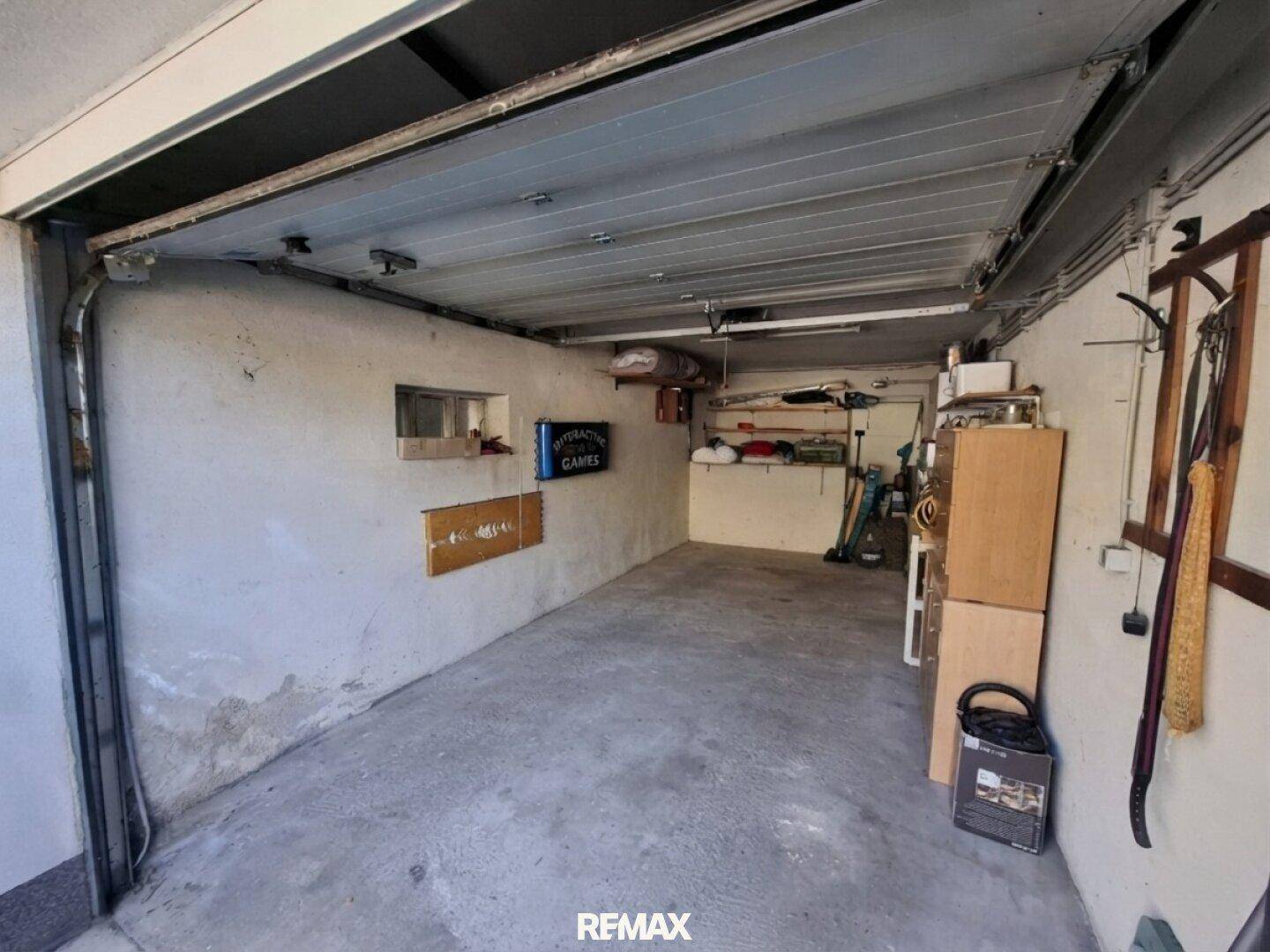 Geräumige Garage mit Betonboden und Stauraum, ideal für Fahrzeuge und diverse Gegenstände.