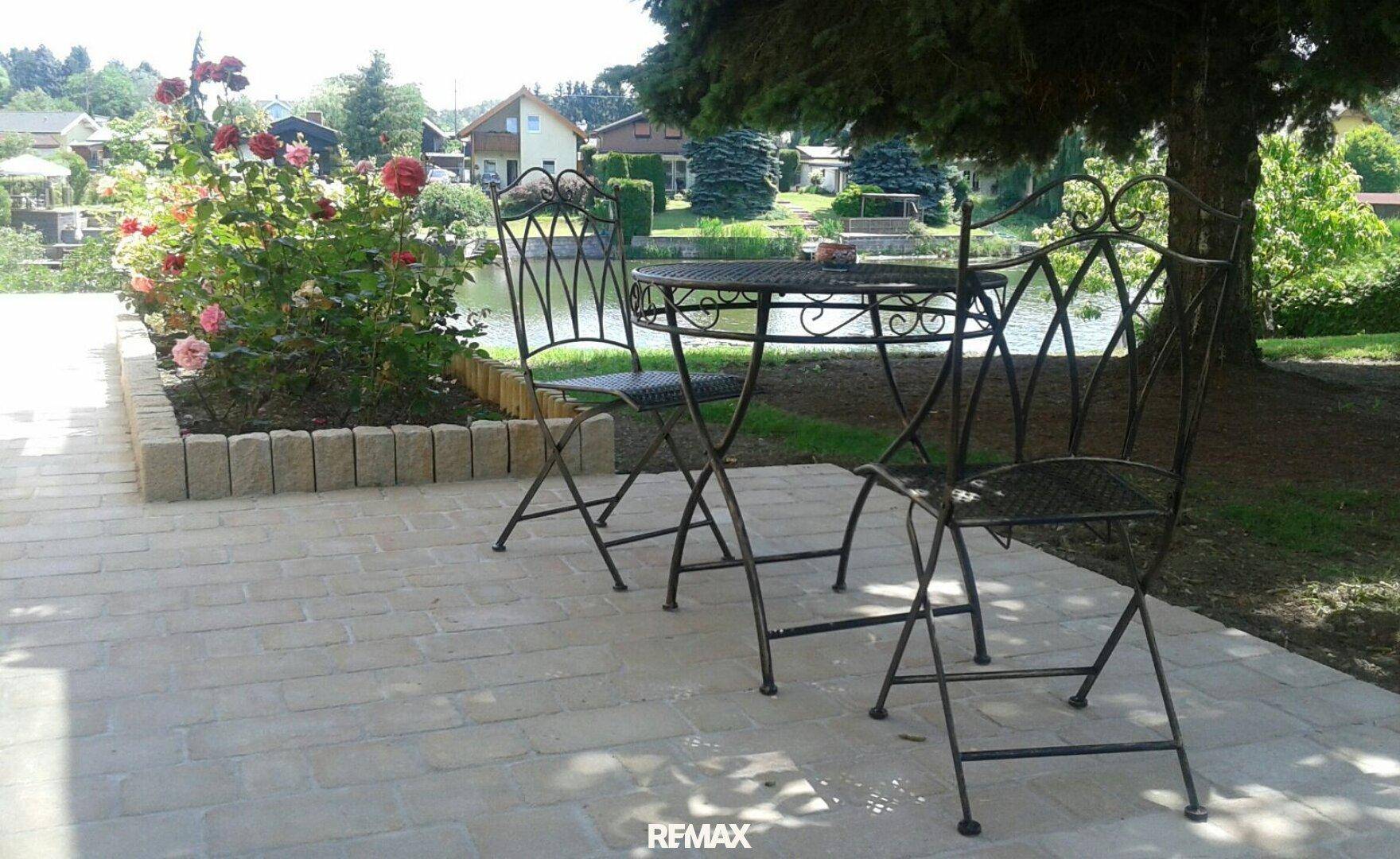 Gemütliche Terrasse mit schmiedeeisernen Gartenmöbeln und direktem Blick auf den See.